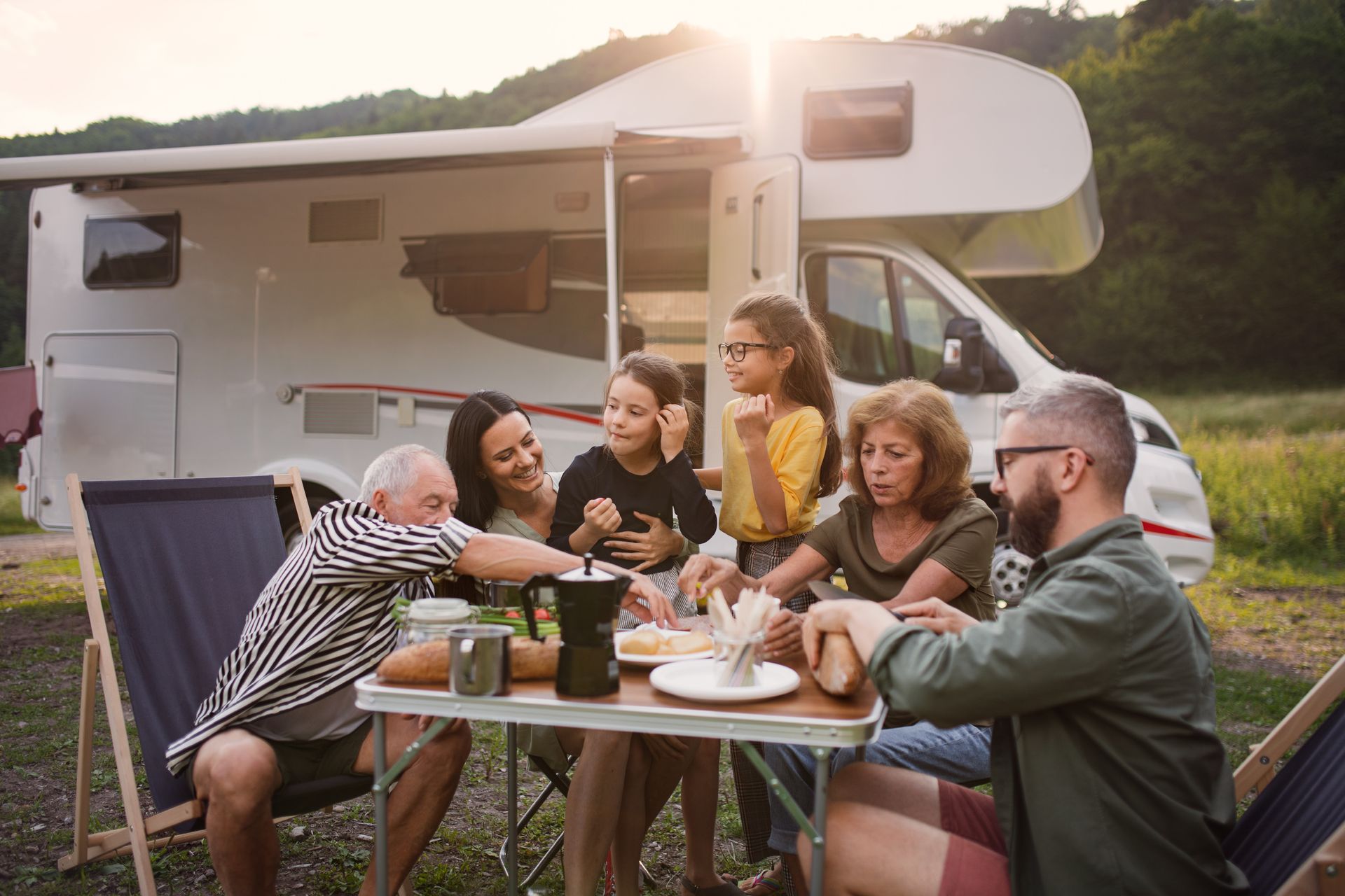 A group of people are sitting at a table in front of a rv.