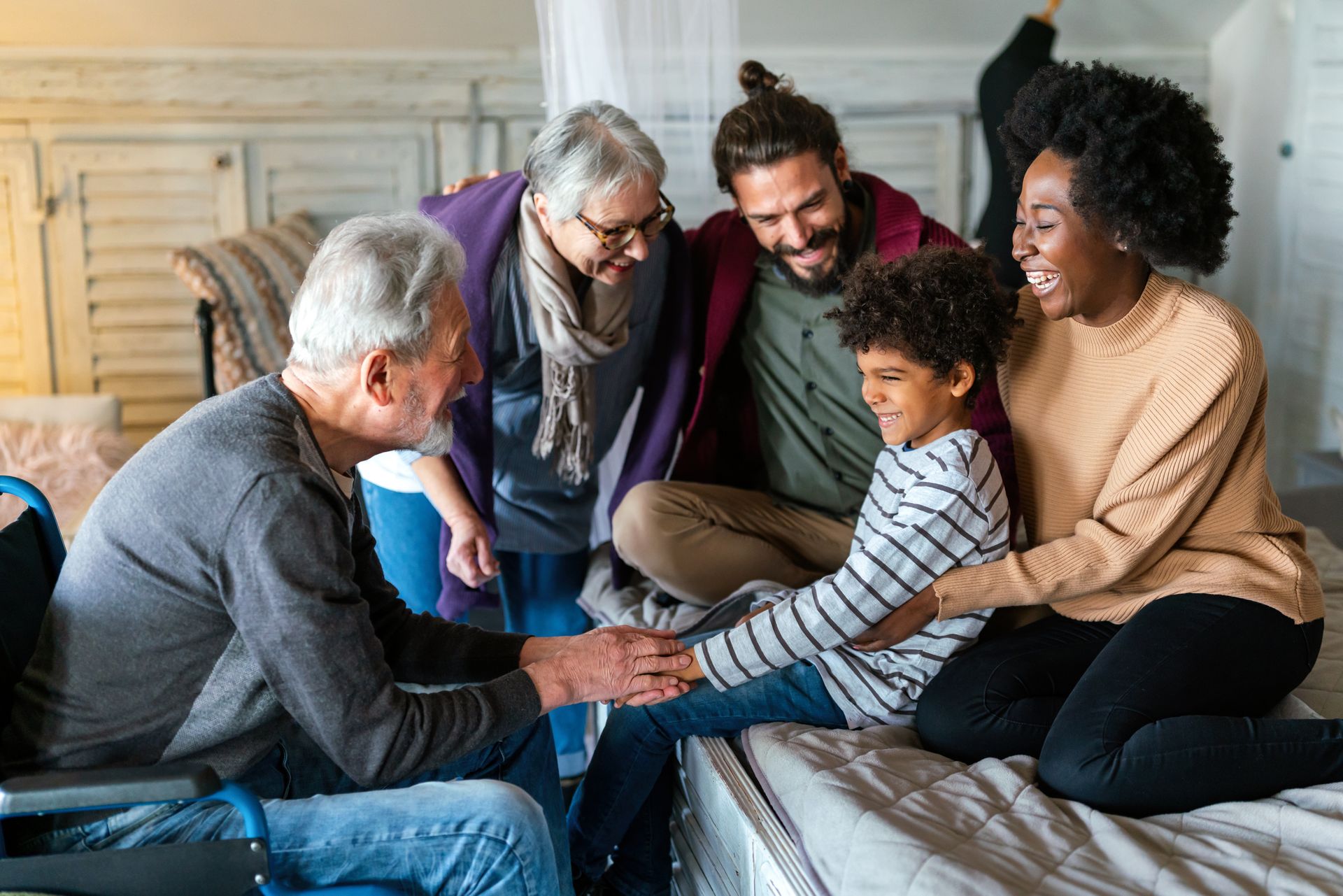 A group of people are sitting on a bed holding hands.