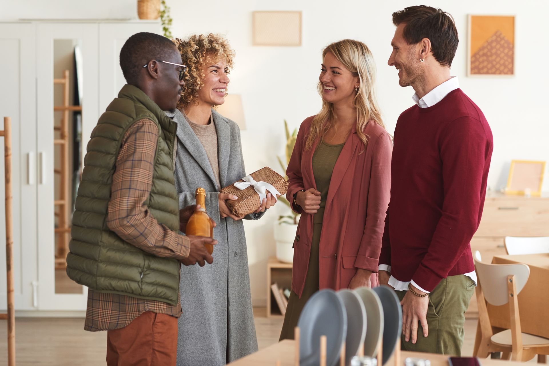 A group of people are standing in a living room talking to each other.