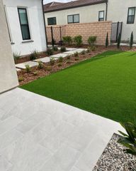 A backyard with a lush green lawn and a brick wall.