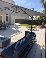 A patio with a couch , table and chairs under an umbrella.