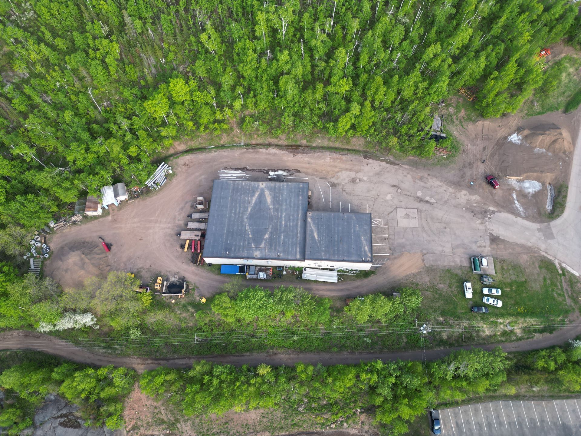Aerial view of a building surrounded by trees and dirt. Vehicles and debris are scattered around the structure.