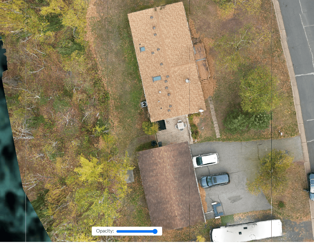 Aerial view of a brown-roofed house and a separate garage with cars parked in the driveway.