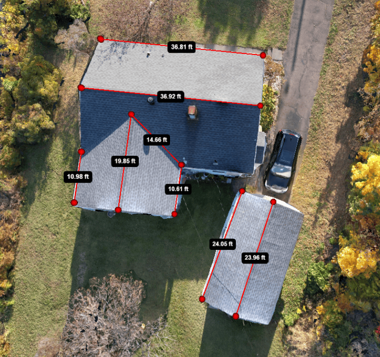 Aerial view of a house and detached garage with roof measurements, surrounded by trees and a driveway.