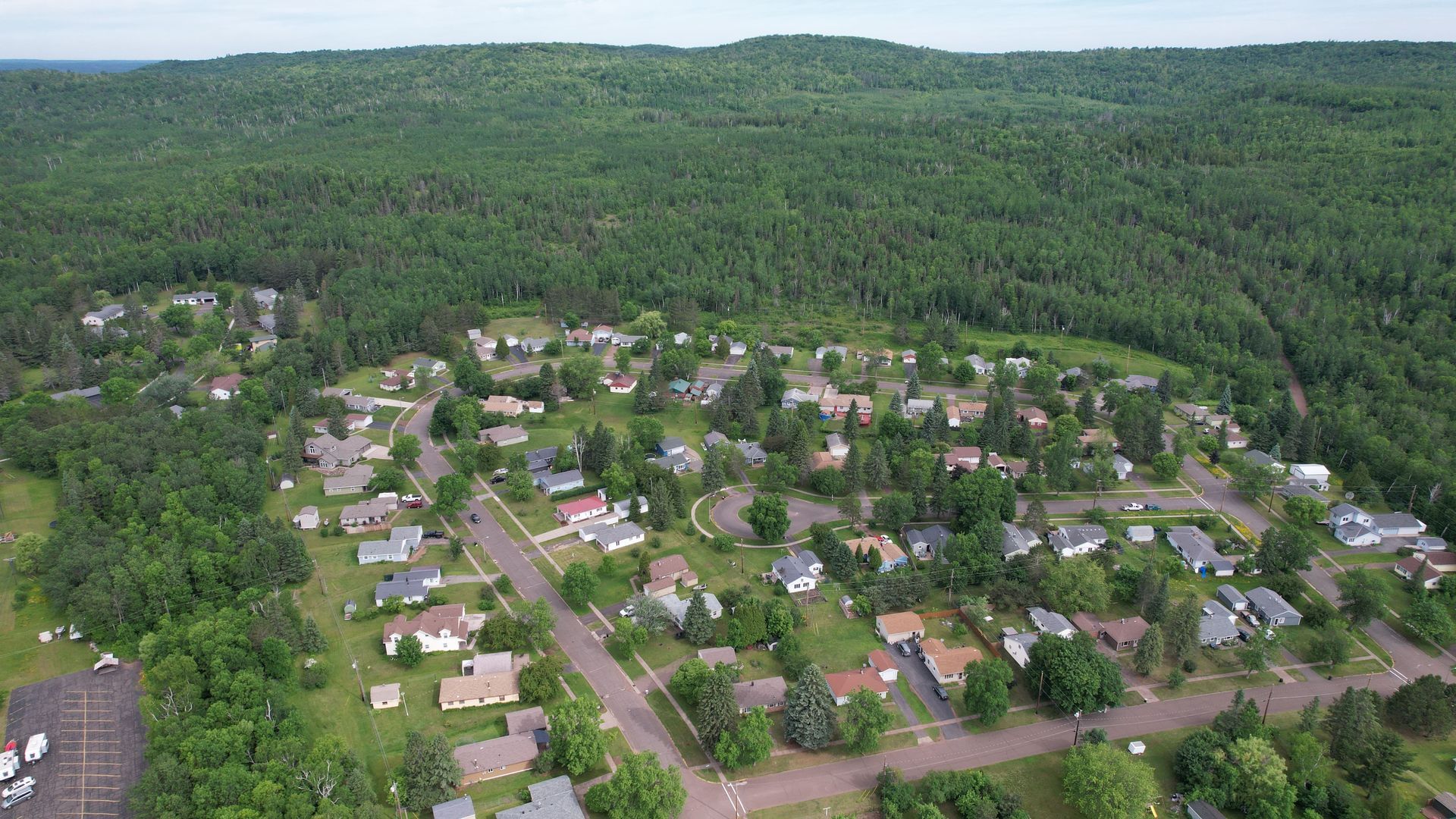 Aerial view of a residential neighborhood surrounded by a dense green forest.