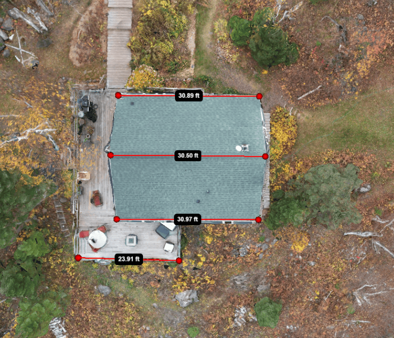 Overhead view of a cabin with measurements marked. It has a green roof and a wooden deck.