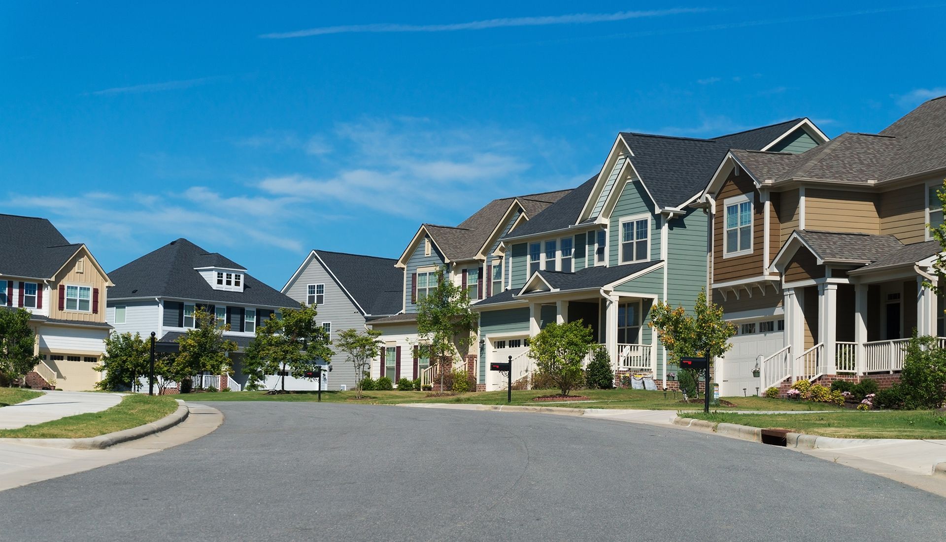 Row of suburban houses on a sunny street, blue sky overhead.