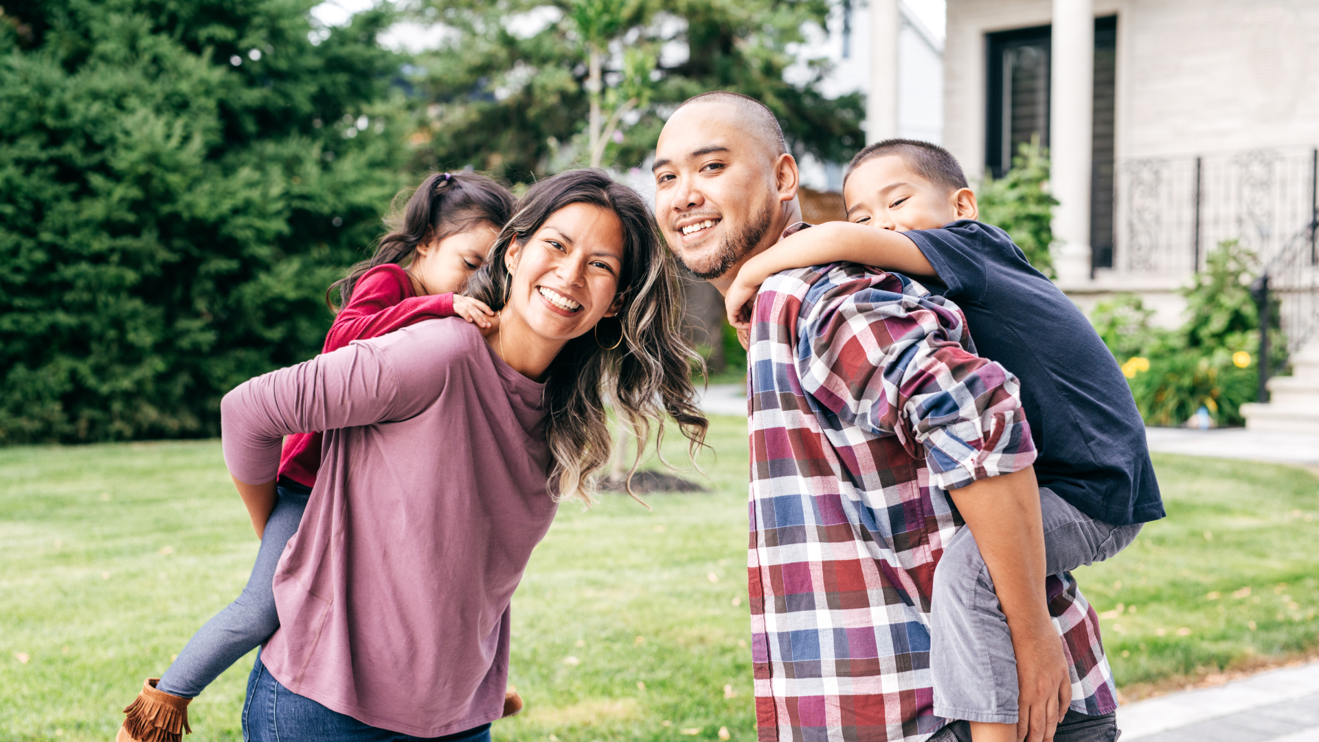 a family is posing for a picture in front of their house .