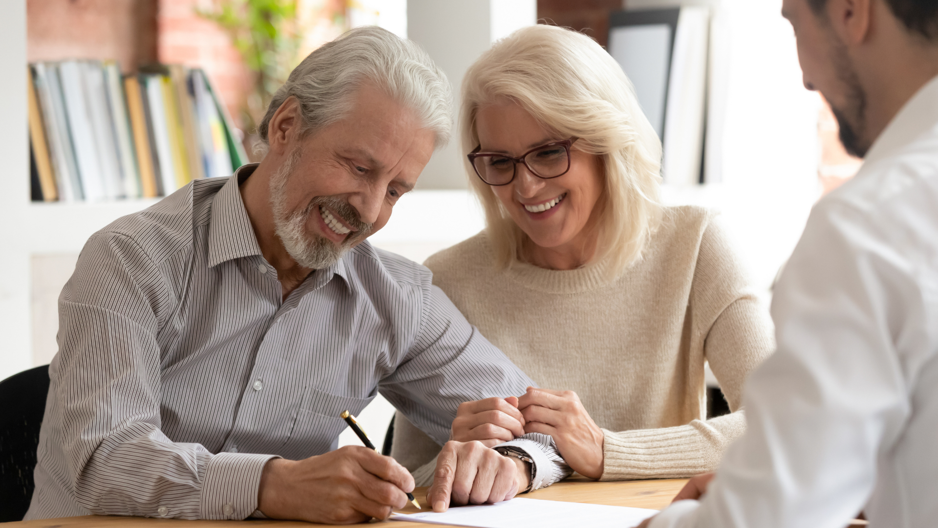 an elderly couple is signing a document with a man .