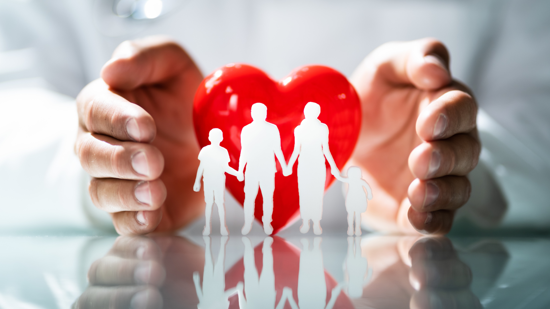 a person is holding a paper cut out of a family and a red heart .