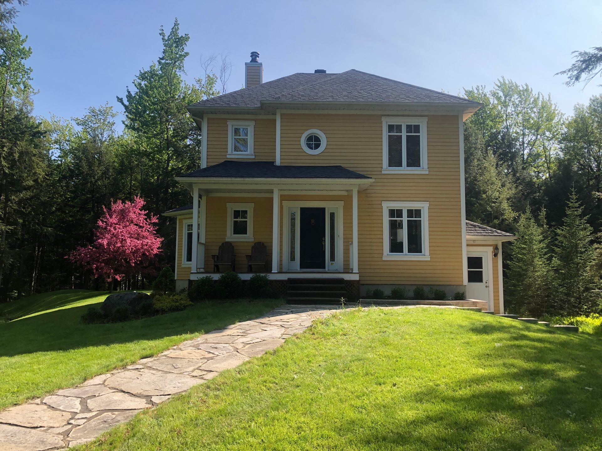 Une grande maison jaune avec une allée en pierre qui y mène