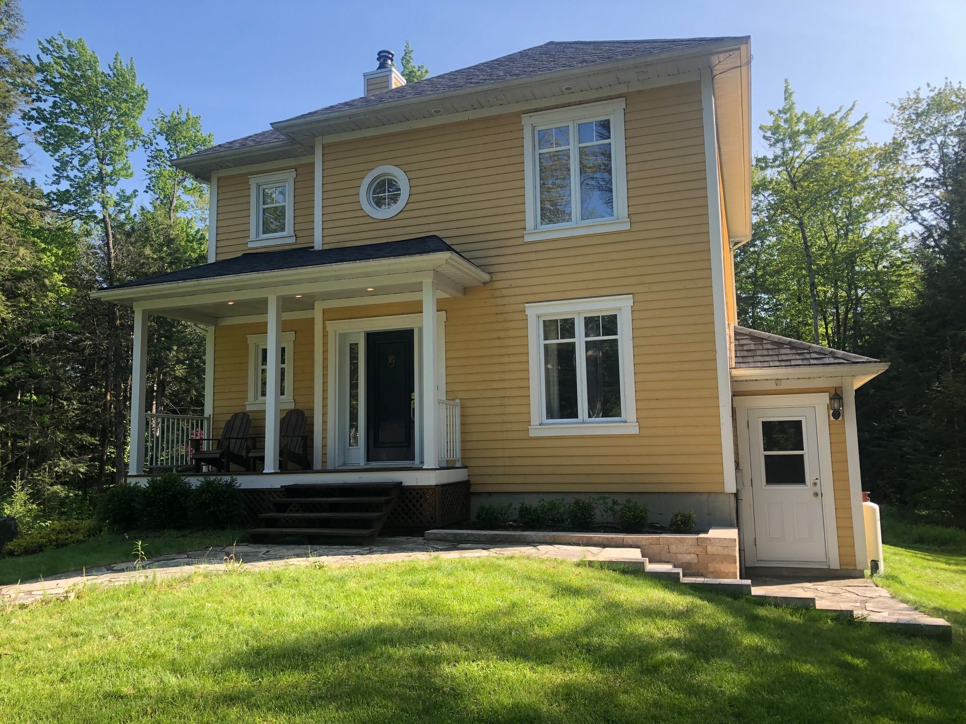 Une grande maison jaune avec un porche et des escaliers