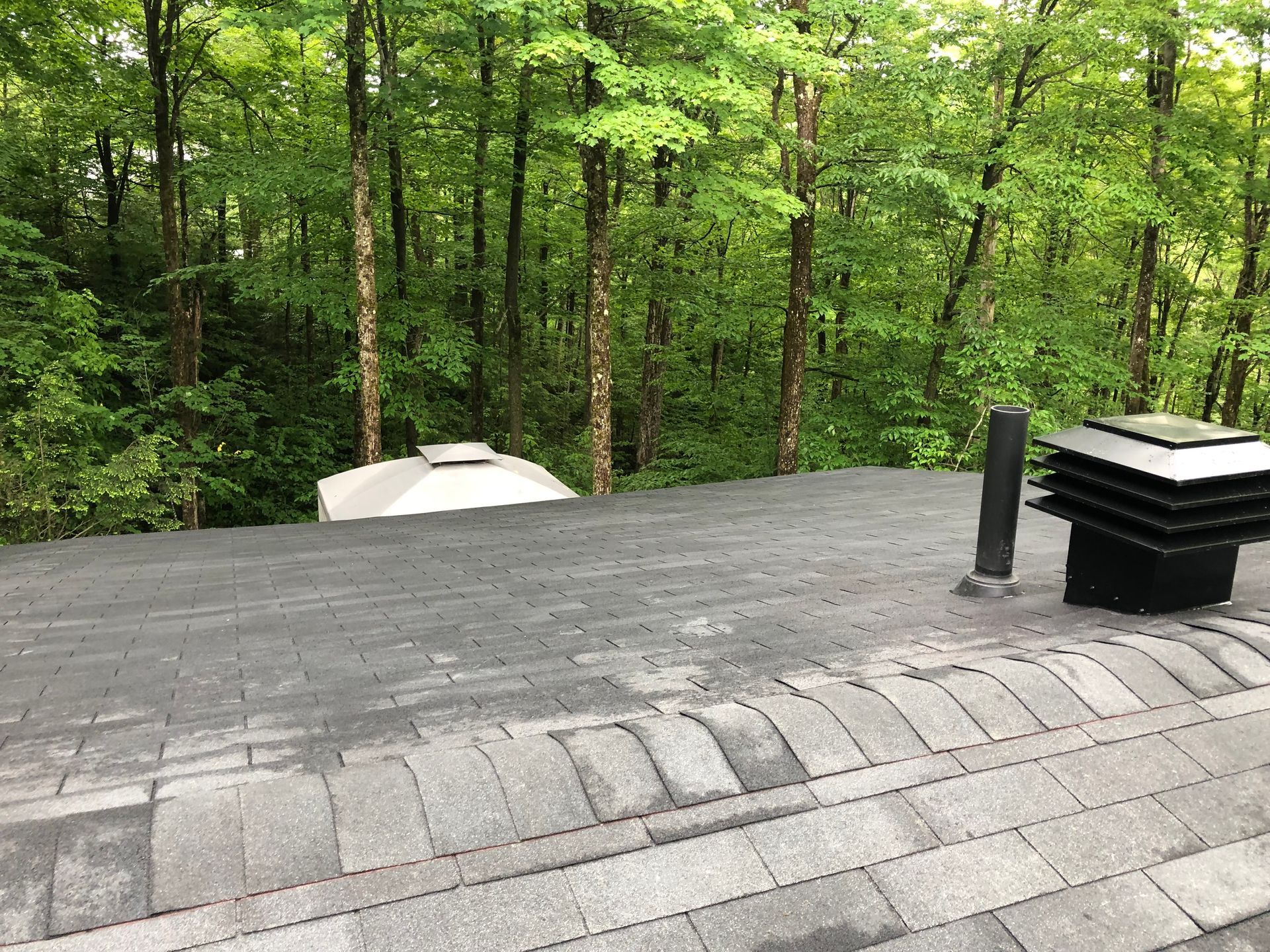 Un toit avec une cheminée dessus et des arbres en arrière-plan.