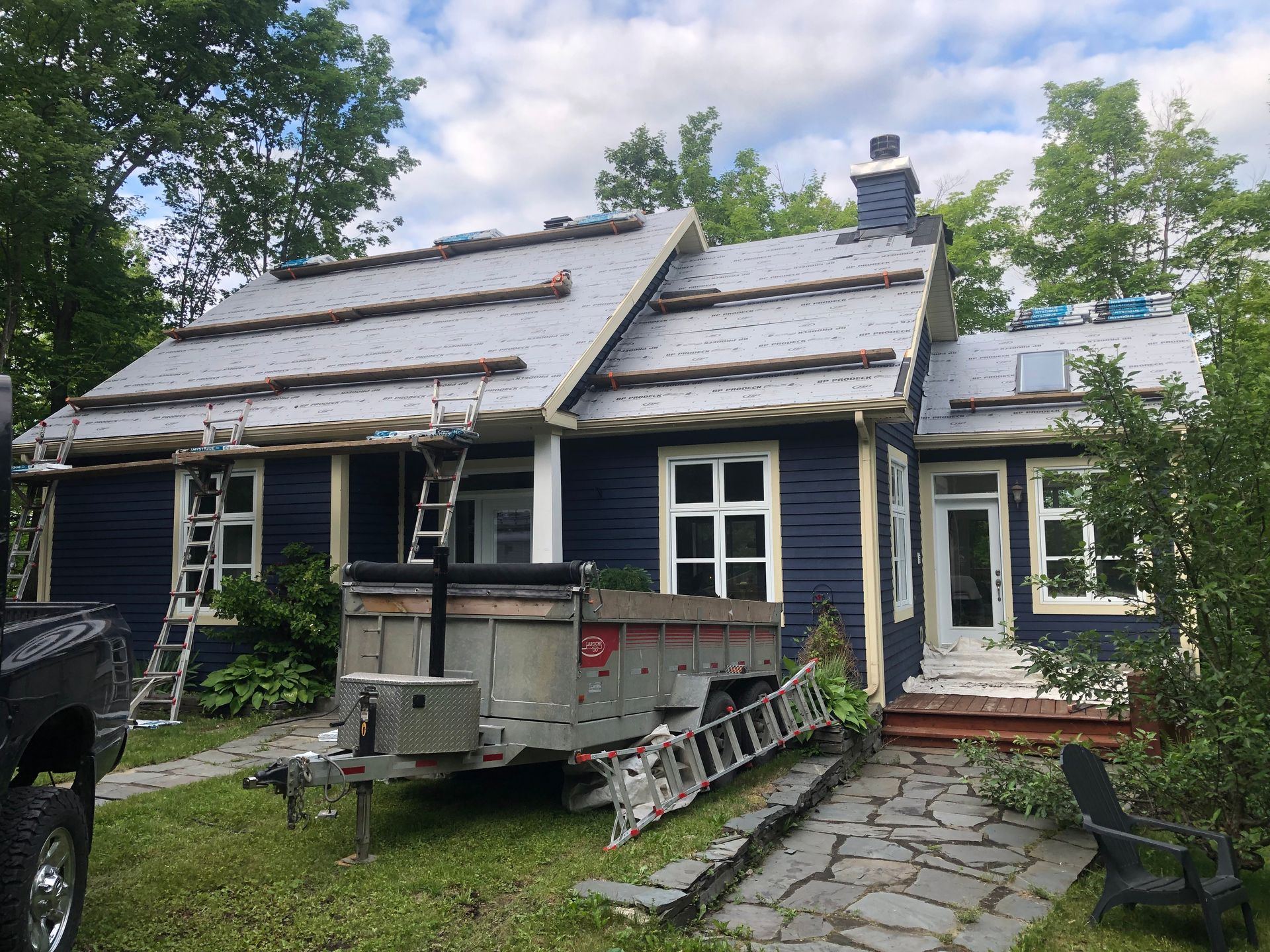 Une maison bleue avec une caravane garée devant.