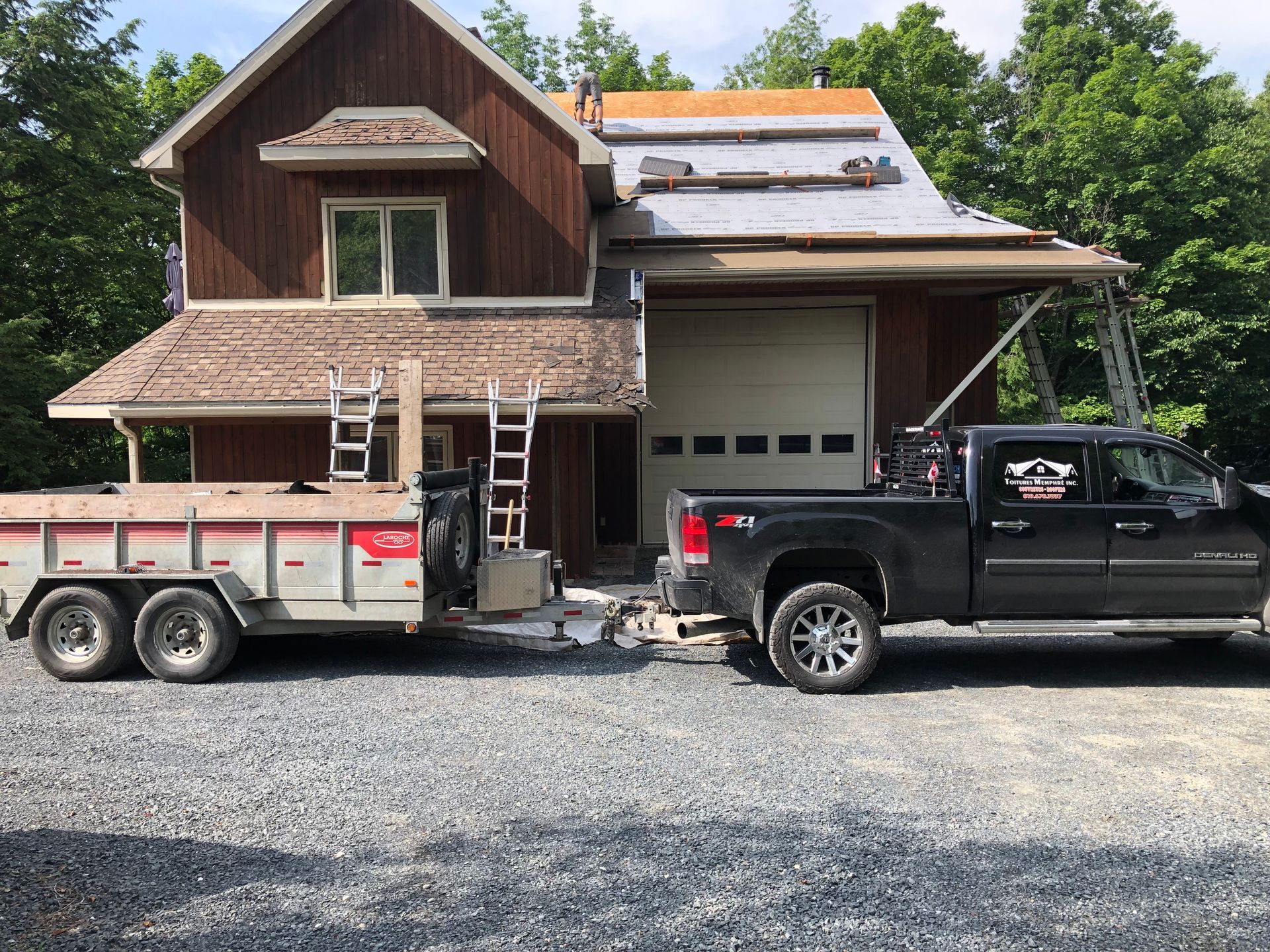 Un camion avec une remorque attachée est garé devant une maison.