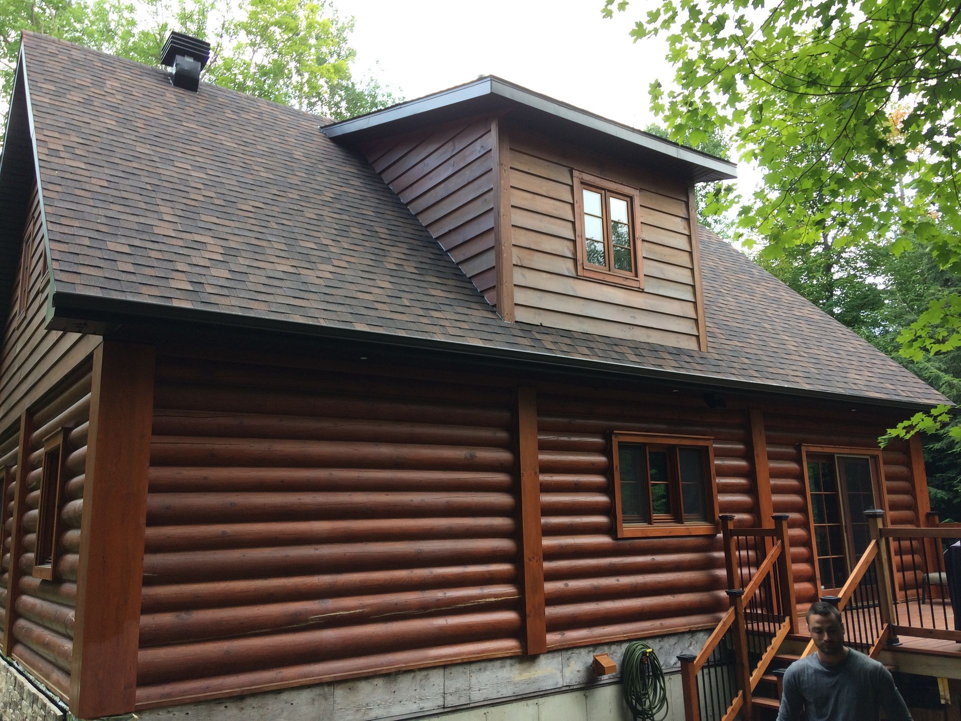 Un homme se tient devant une grande cabane en rondins.
