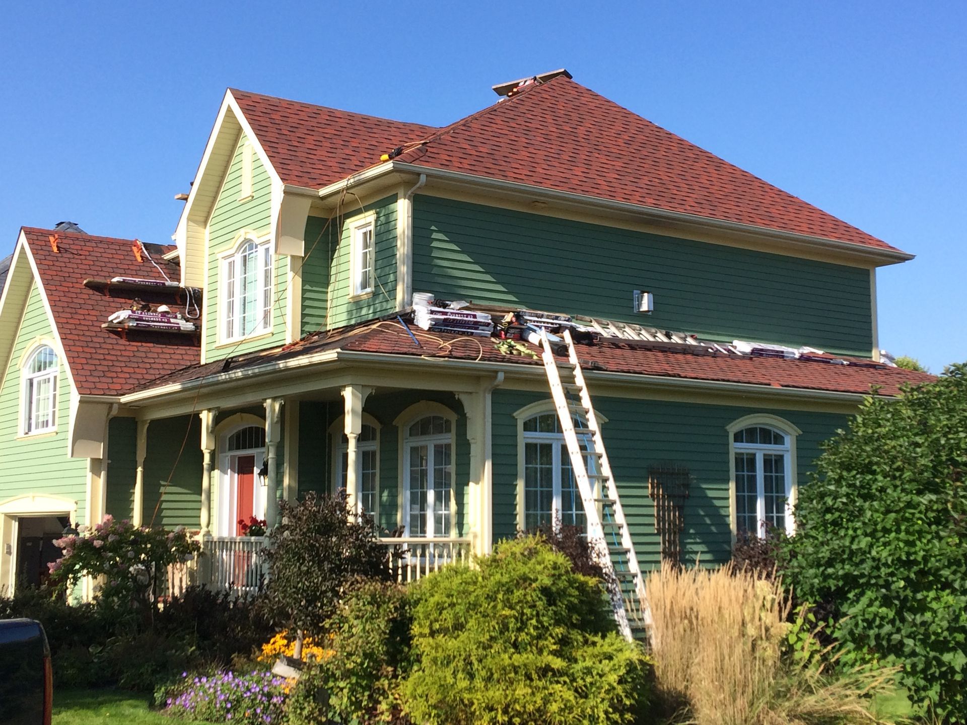 Une maison verte avec un toit rouge est en train d'être peinte