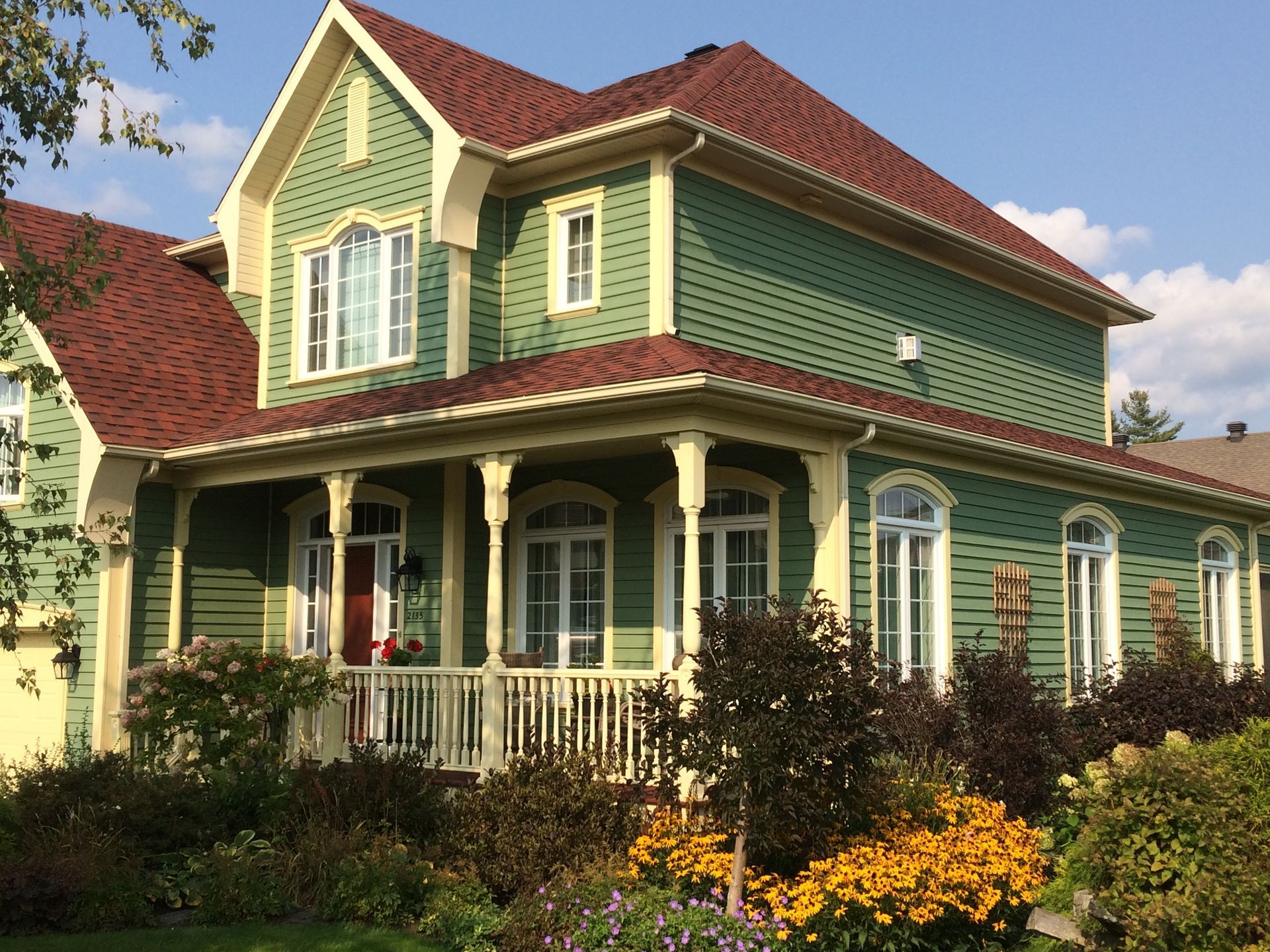 Une grande maison verte avec un toit rouge
