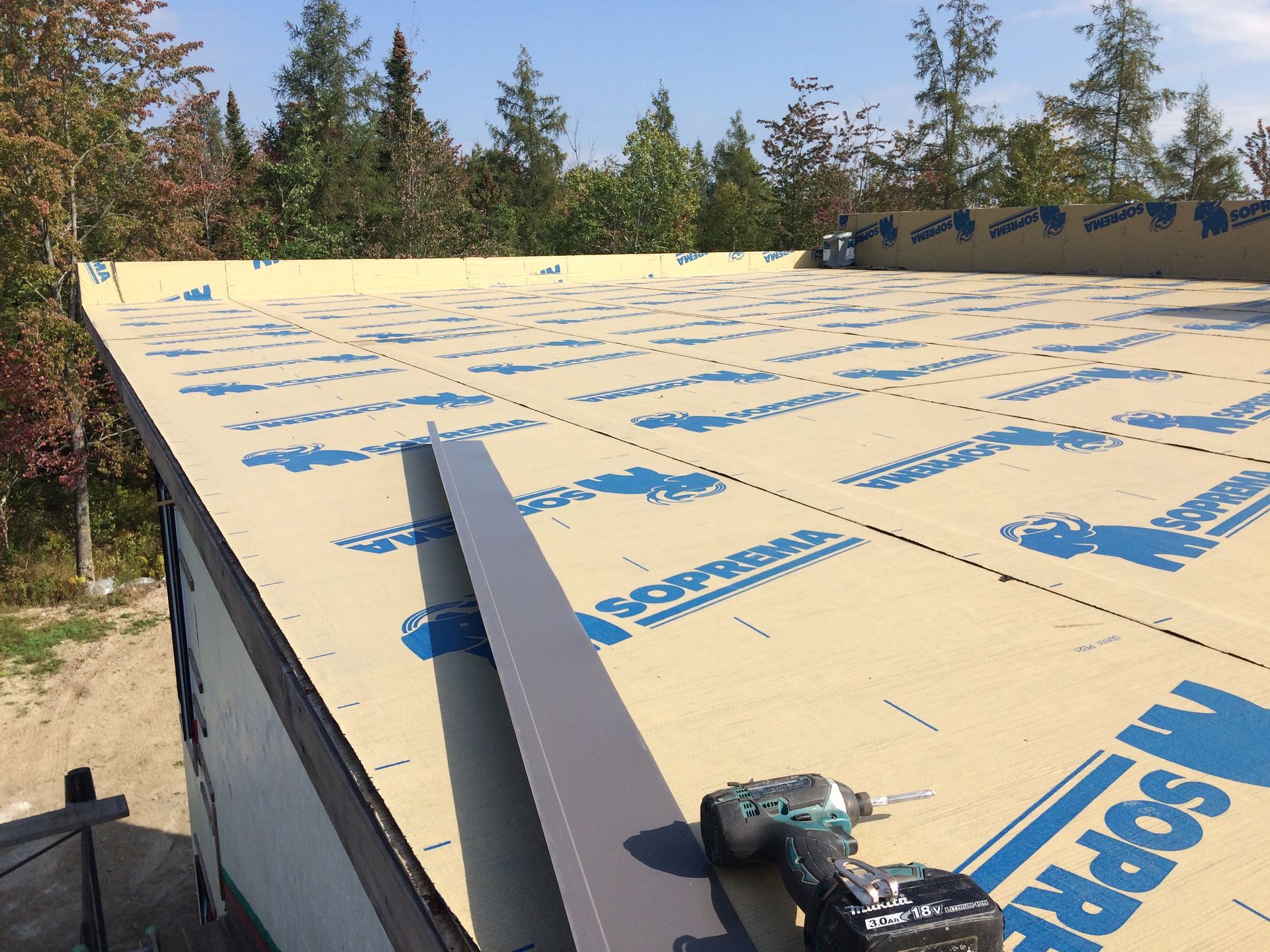 Une perceuse est posée sur un toit avec un matériau de toiture portant l'inscription « maspre »