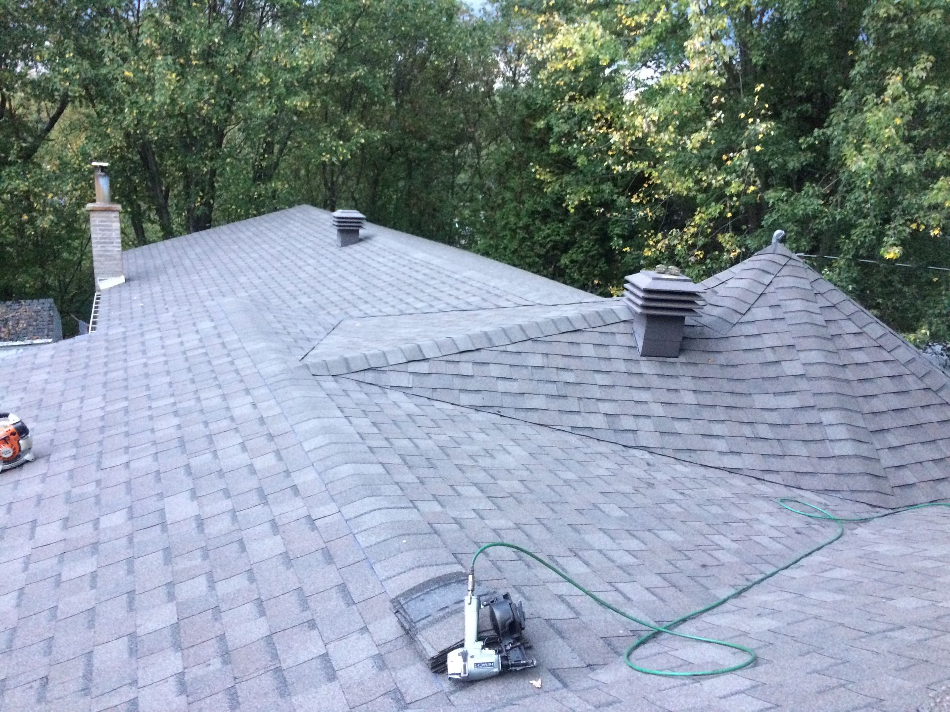 Un toit avec un tuyau attaché et des arbres en arrière-plan.