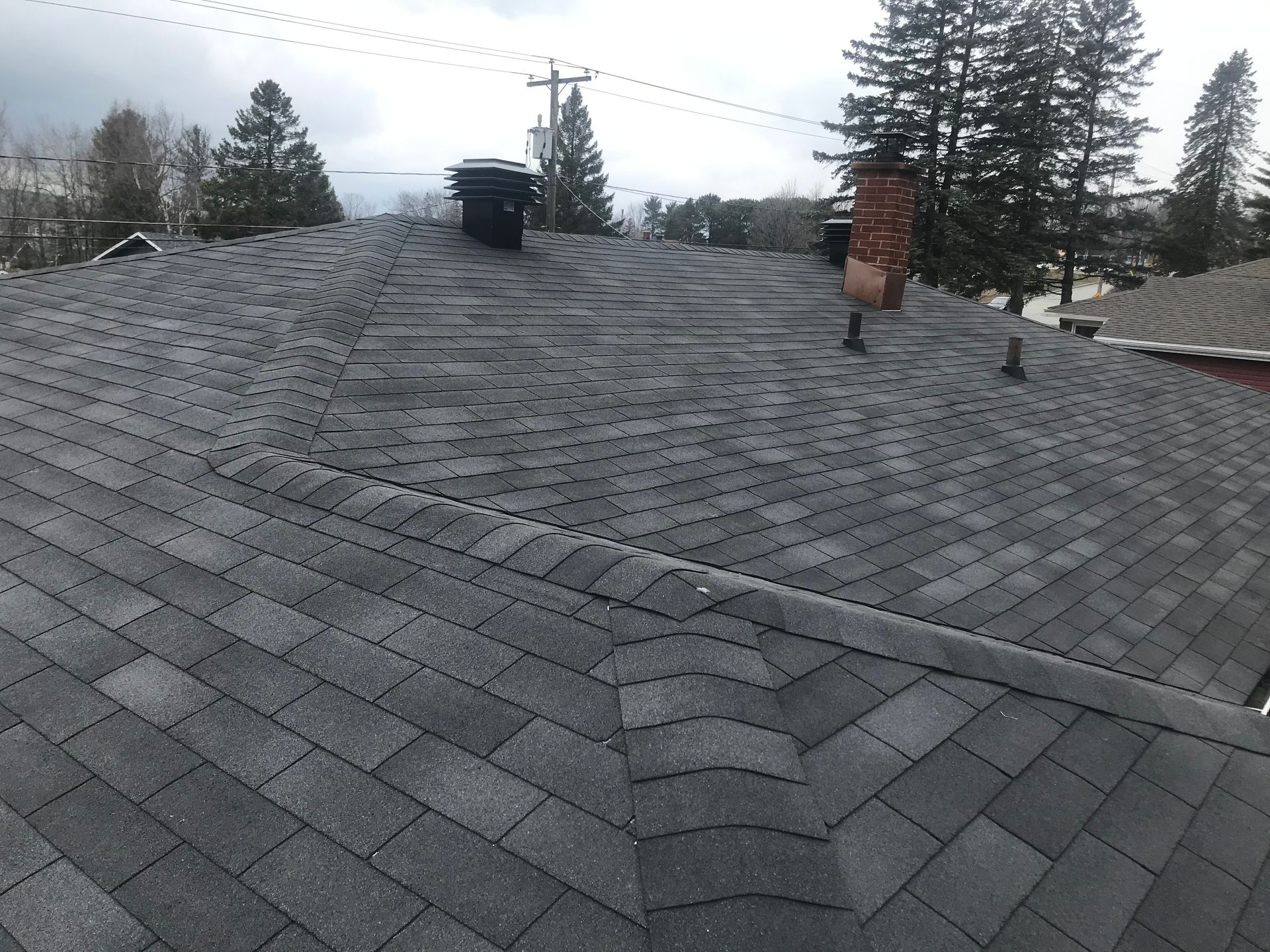 Un toit avec une cheminée au-dessus et des arbres en arrière-plan.