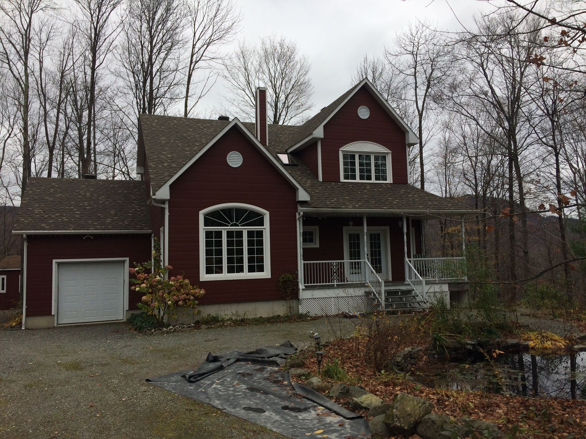 Une grande maison rouge avec un garage et un porche