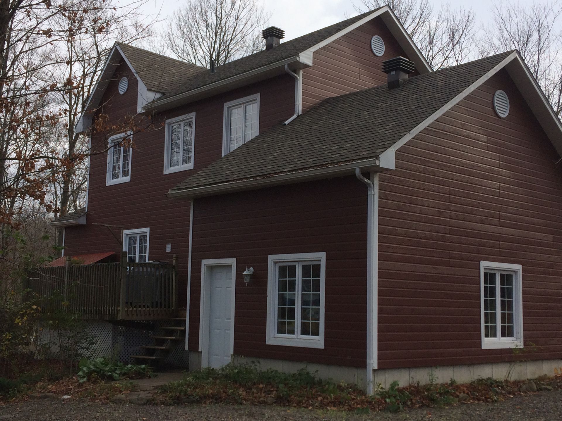 Une maison brune avec un toit gris et des garnitures blanches