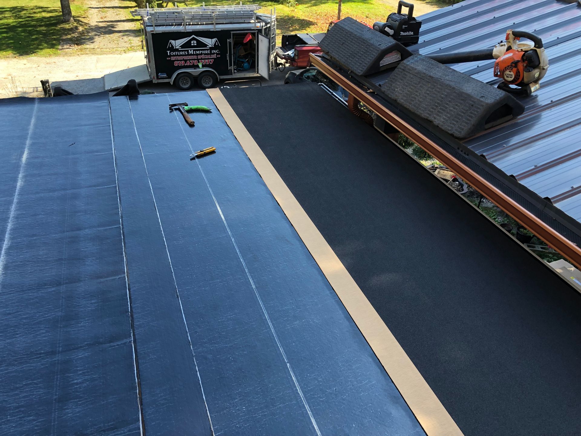 Un toit noir est en train d'être installé sur une maison.