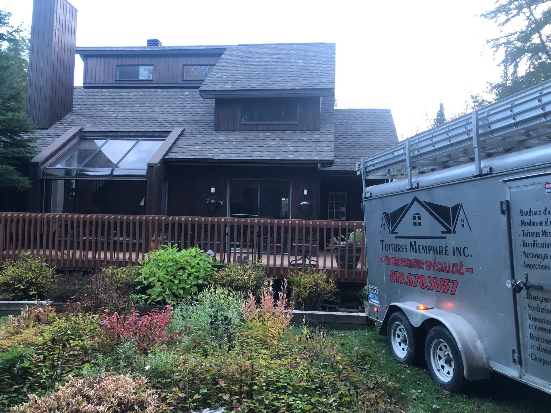 Une remorque est garée devant une grande maison.