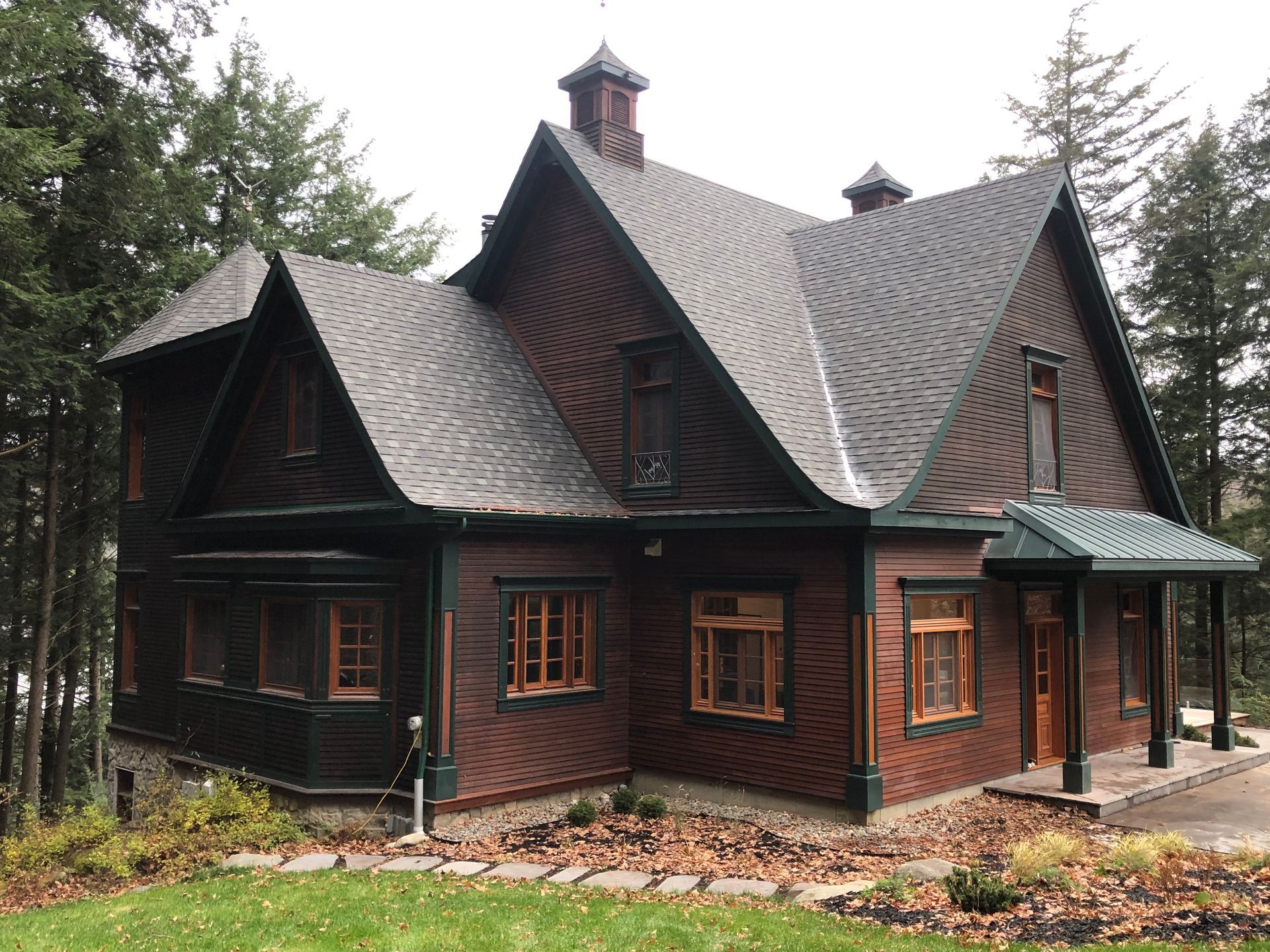 Une grande maison en briques avec un toit gris est entourée d'arbres.