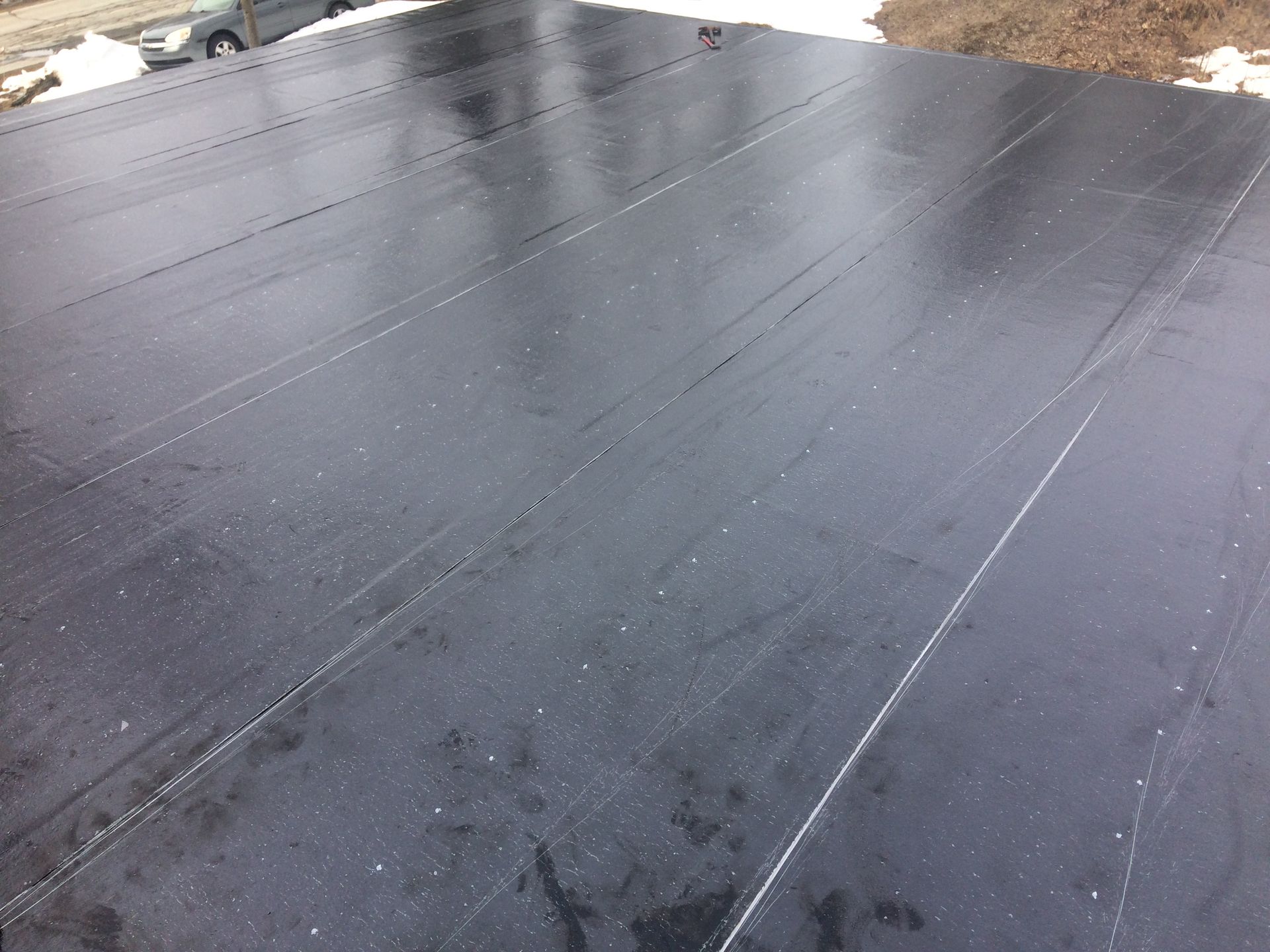 Un toit noir avec une voiture garée en arrière-plan.