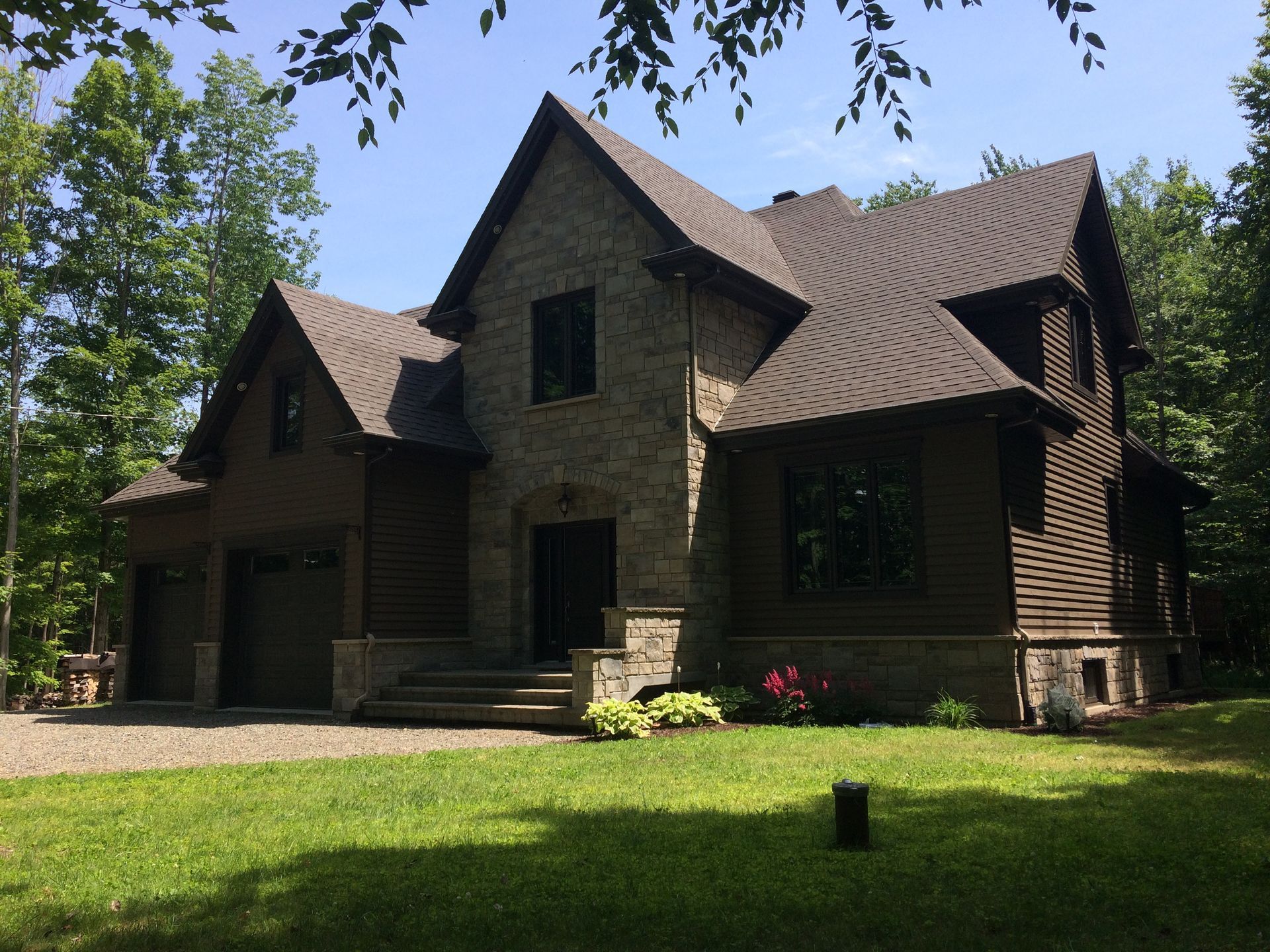 Une grande maison au toit brun est entourée d'arbres