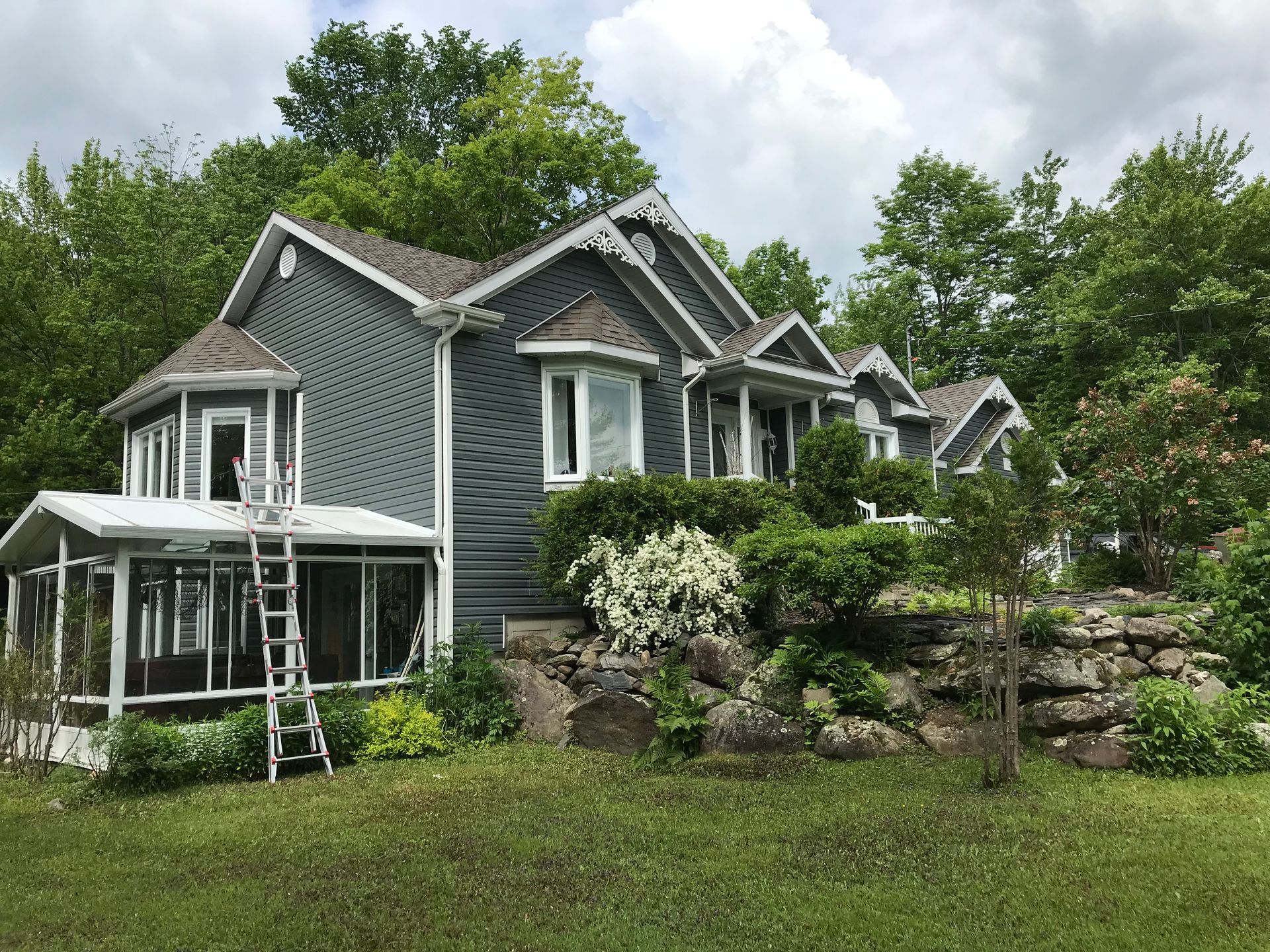 Une grande maison avec un porche grillagé est entourée d'arbres et d'herbe.