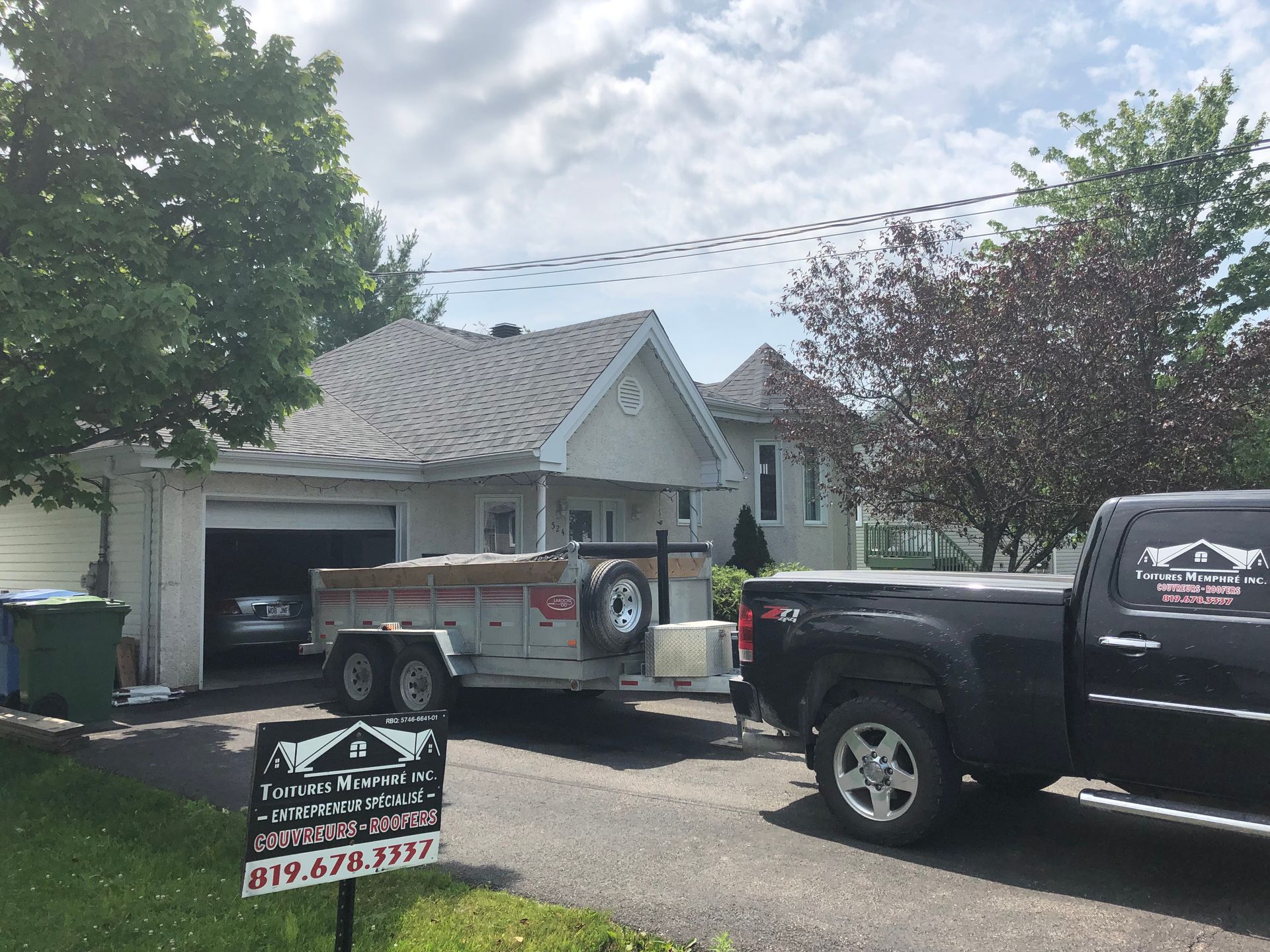 Un camion et une remorque sont garés devant une maison.
