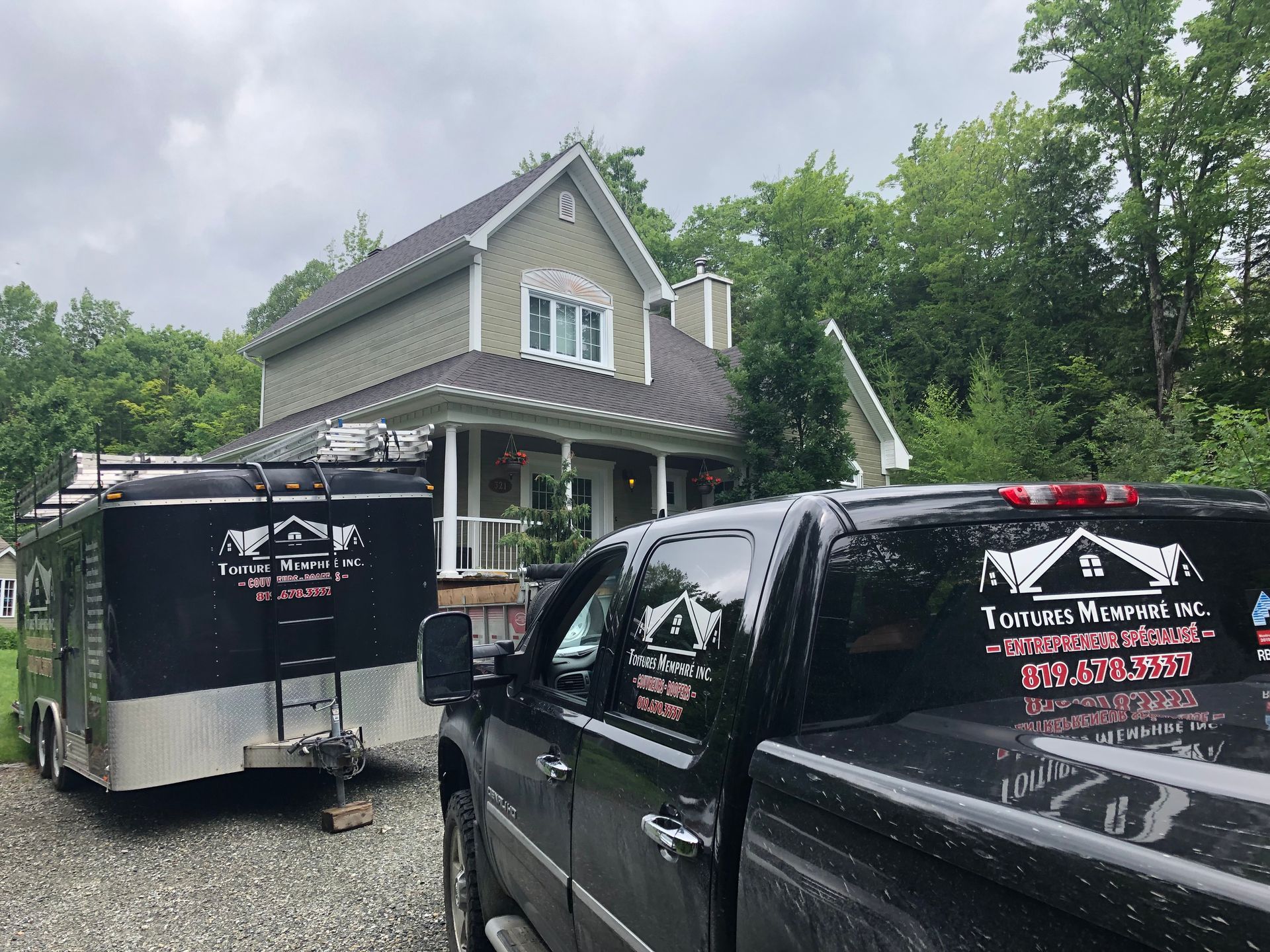 Un camion et une remorque sont garés devant une maison.