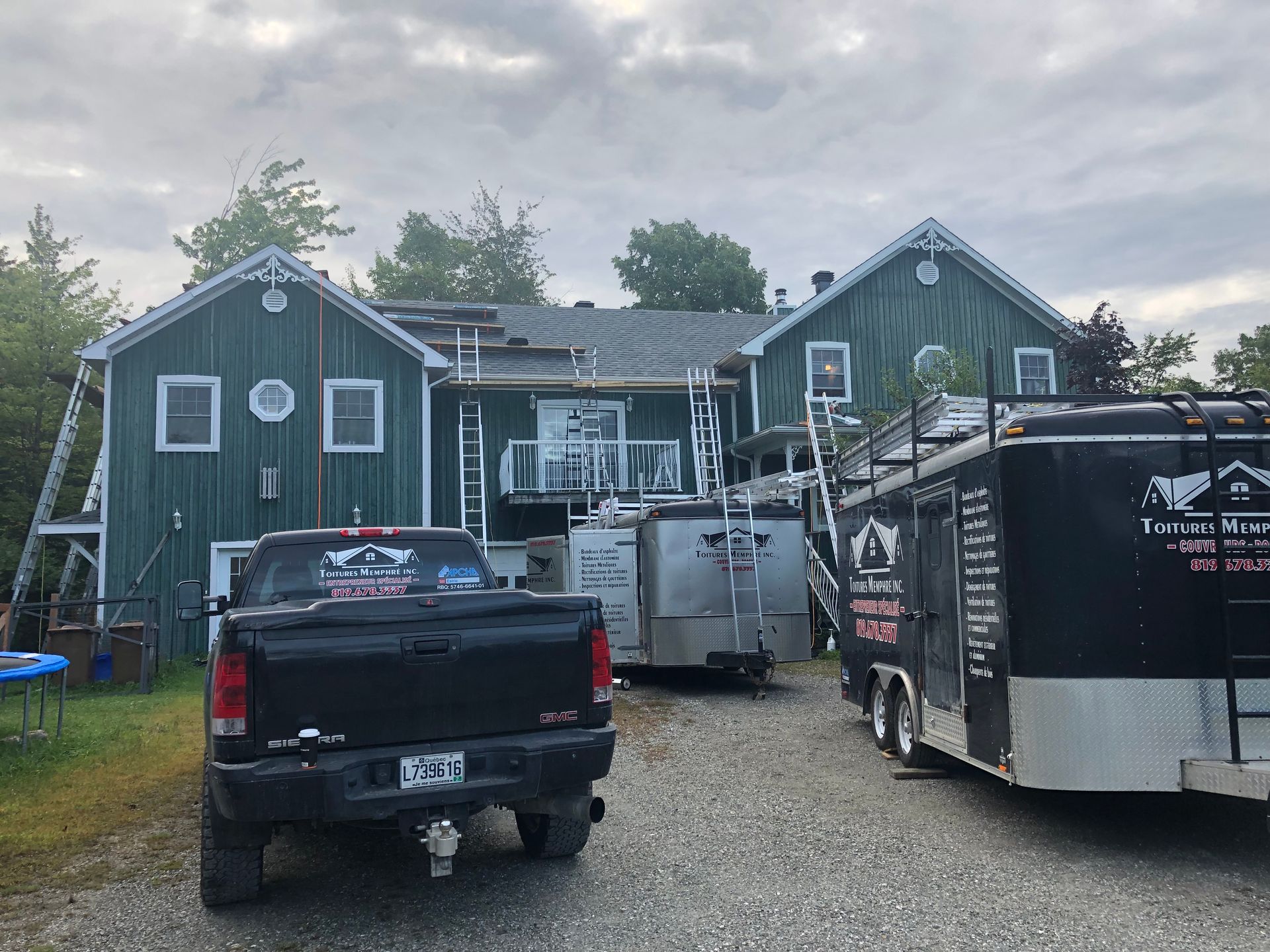 Un camion noir est garé devant une maison verte.