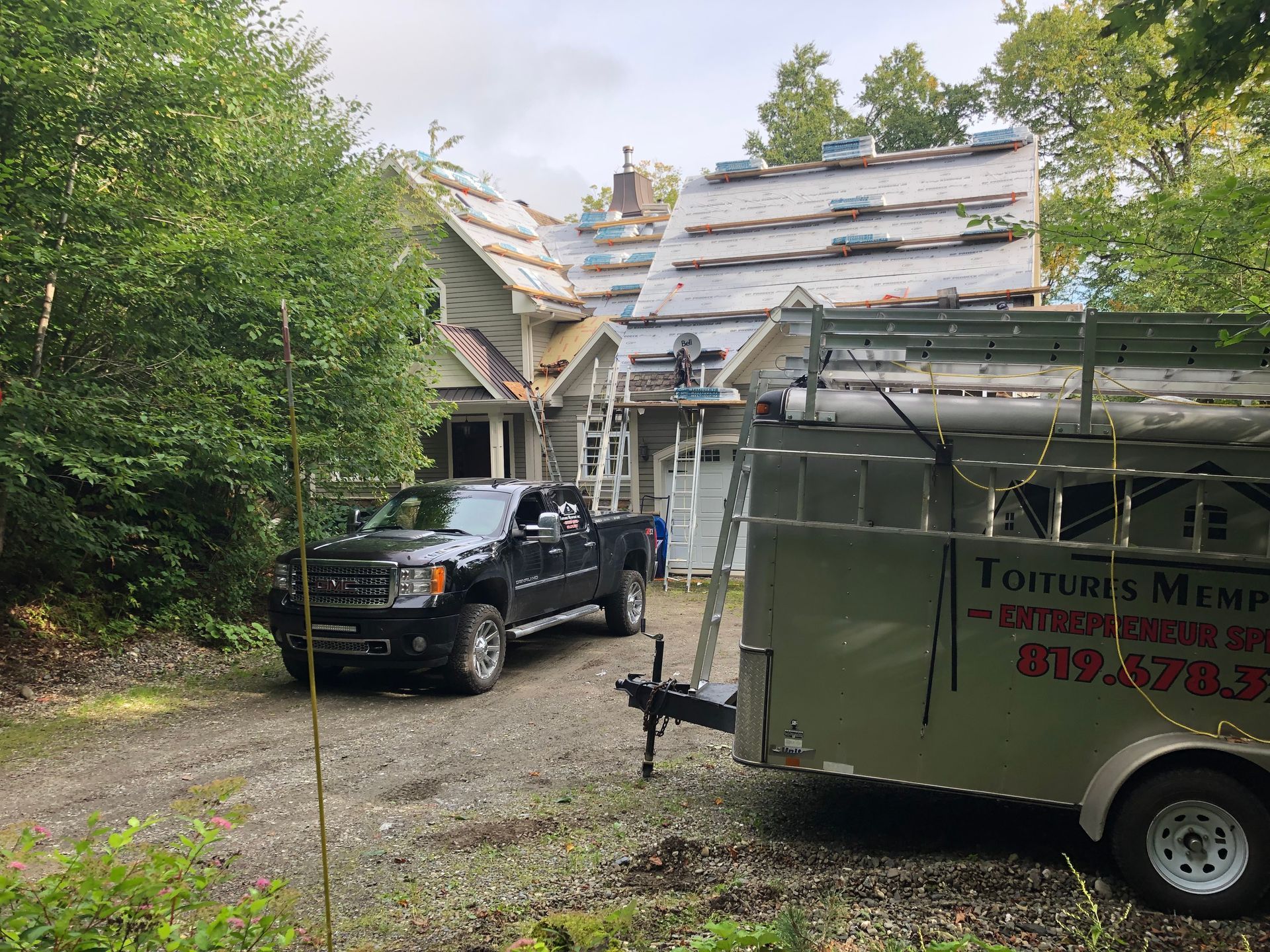 Un camion est garé devant une maison avec une remorque attachée.