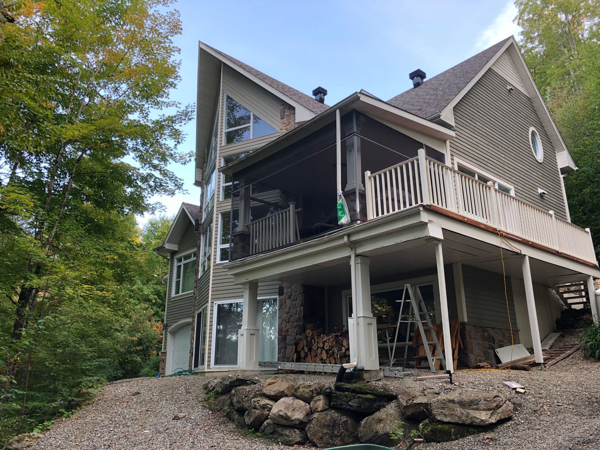 Une grande maison avec une grande terrasse est entourée d'arbres.