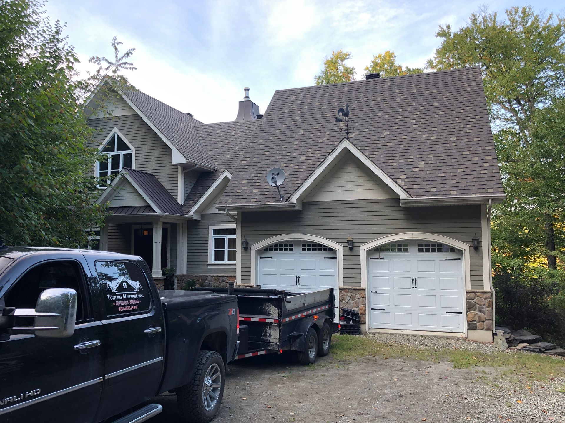 Un camion noir est garé devant une grande maison.