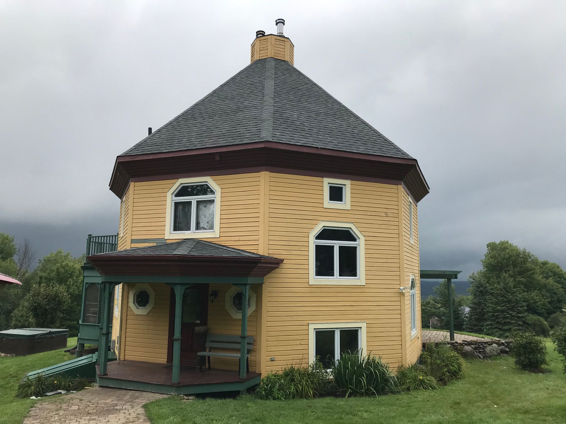 Une maison jaune avec un toit gris et un porche