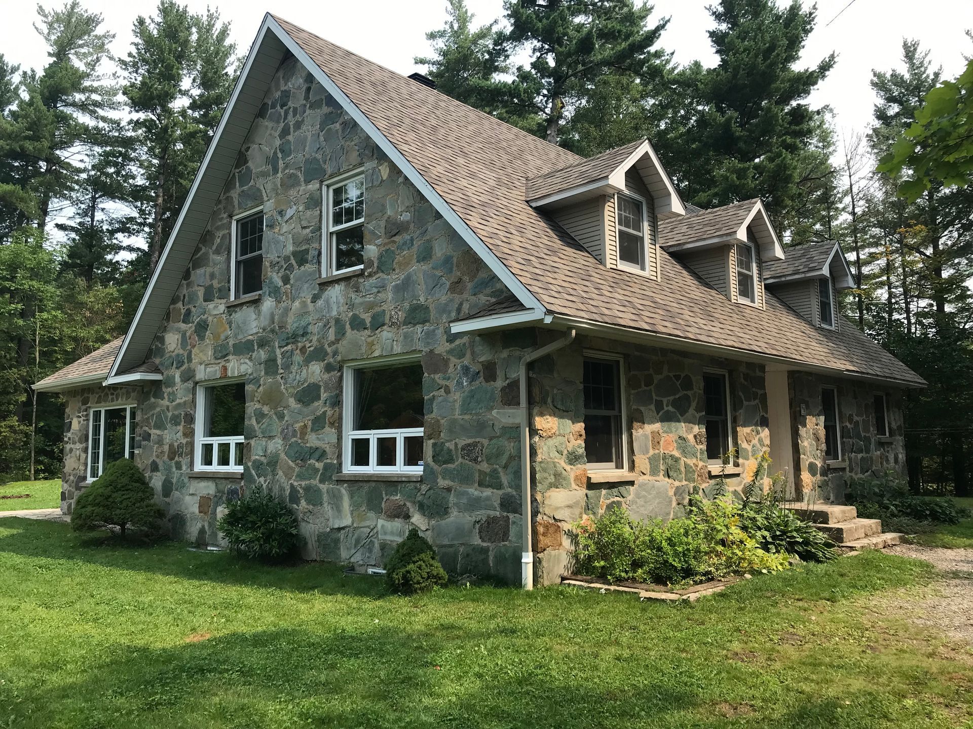 Une grande maison en pierre avec un toit entouré d'arbres.