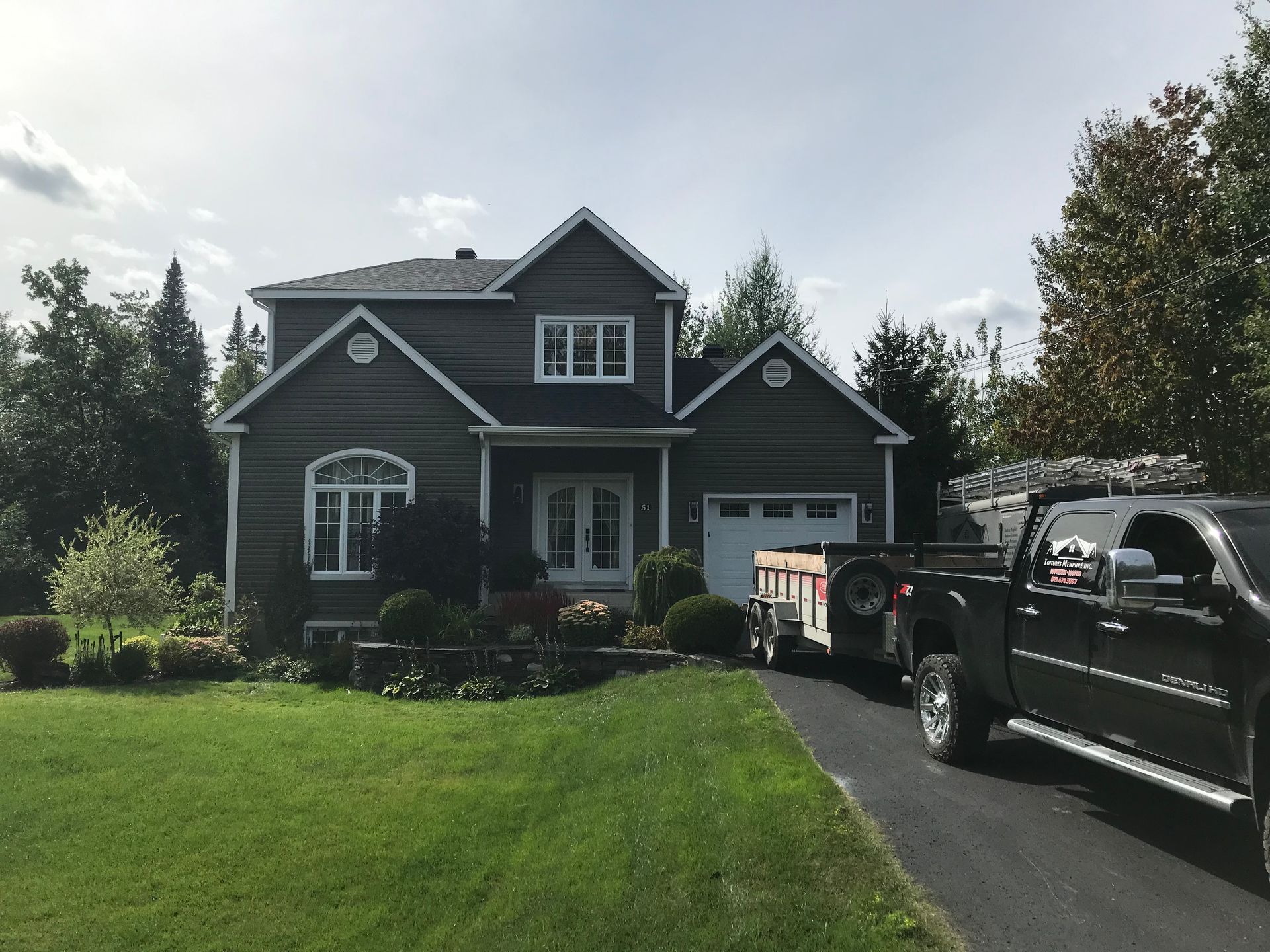 Un camion noir est garé devant une grande maison
