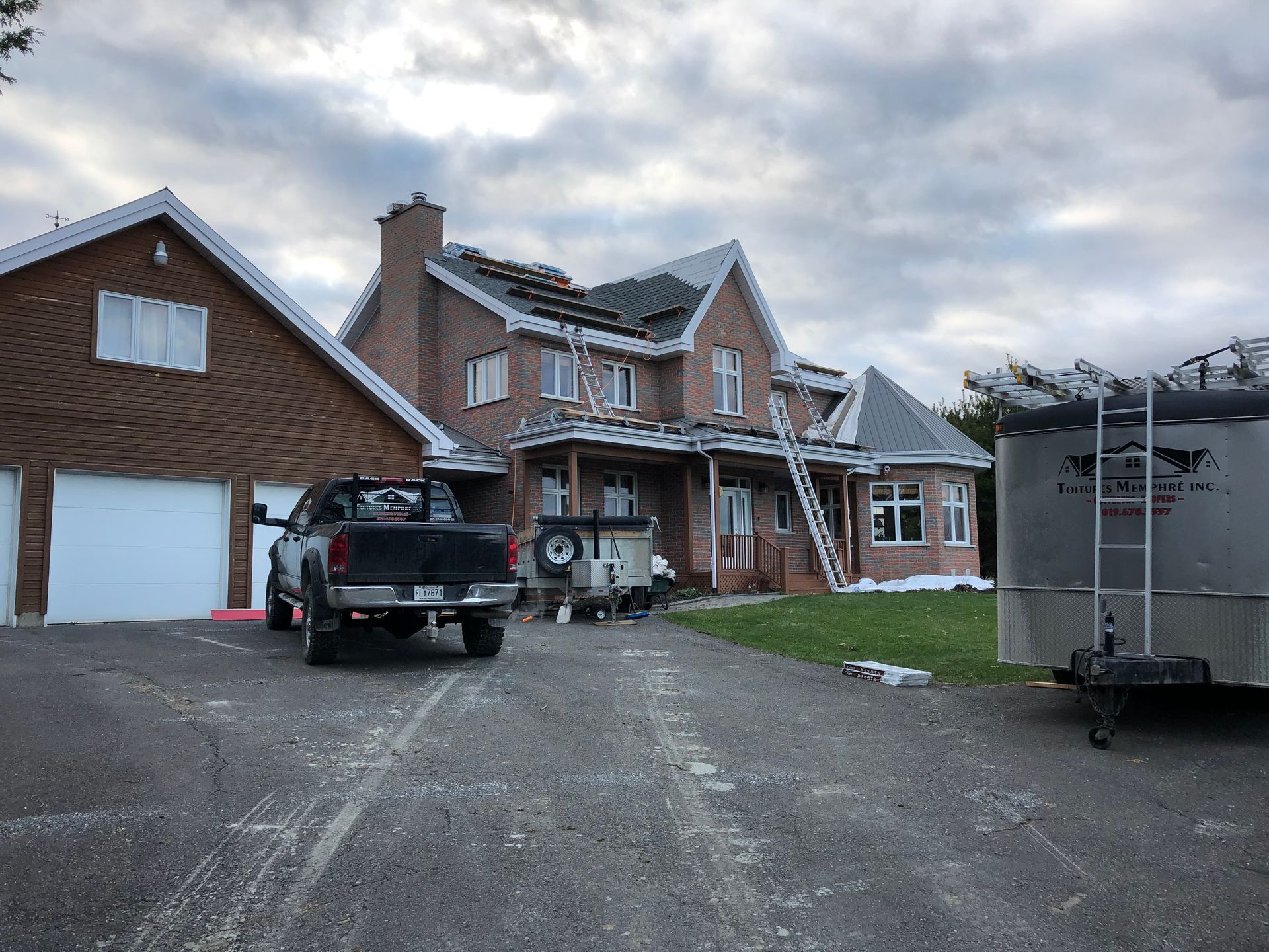 Deux camions sont garés devant une grande maison en briques.