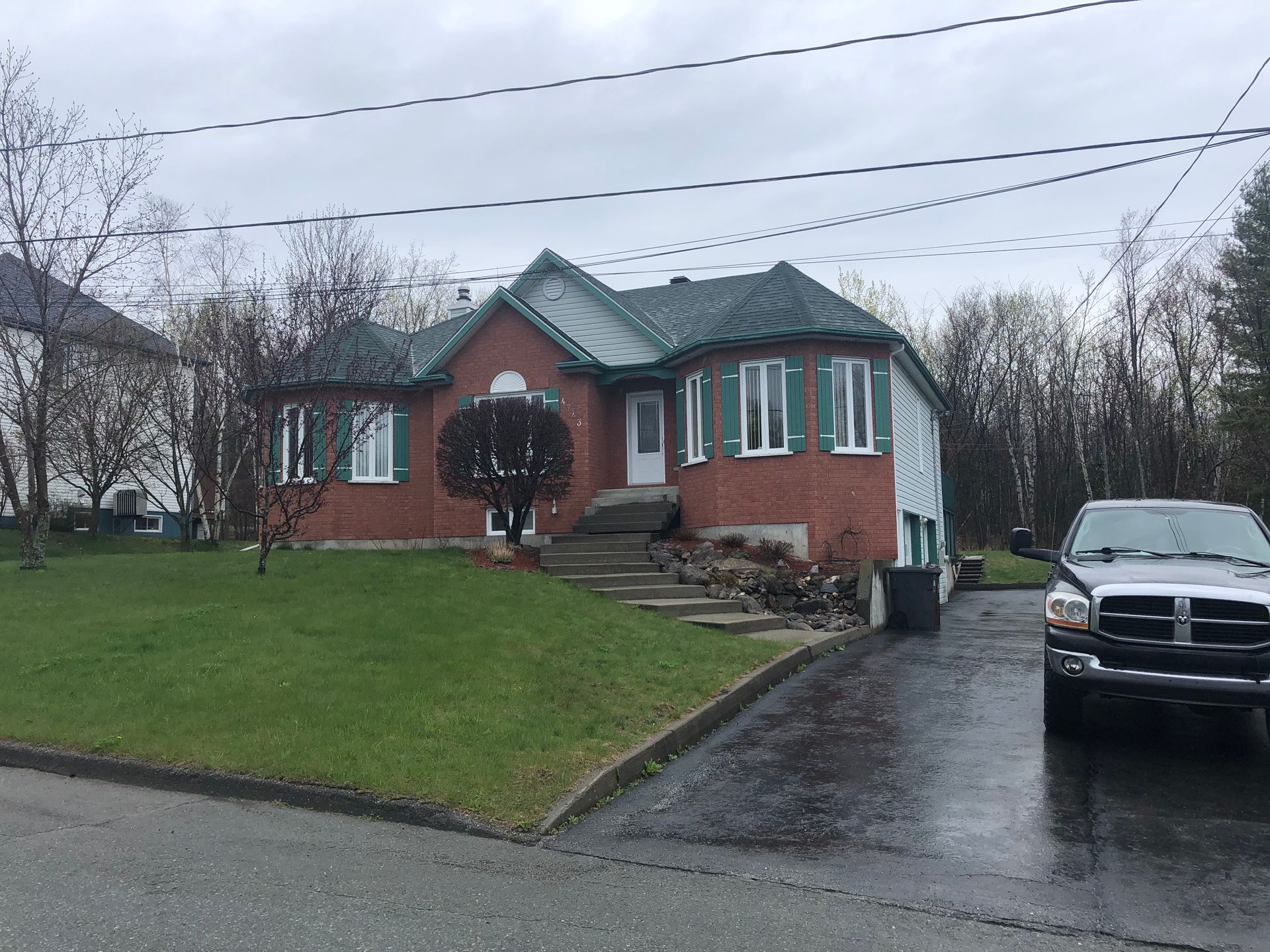 Un camion noir est garé devant une maison en briques.