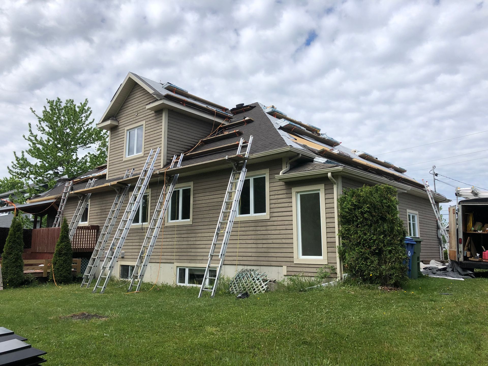 Une maison avec un toit en cours d'installation et une échelle sur le côté.