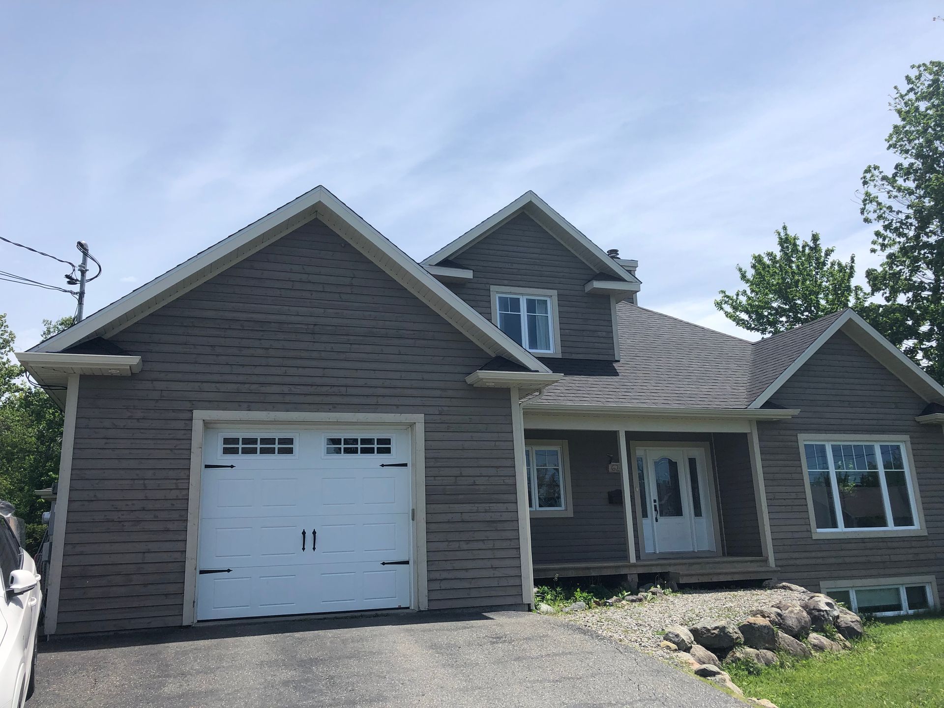 Une maison avec une porte de garage blanche et un revêtement gris