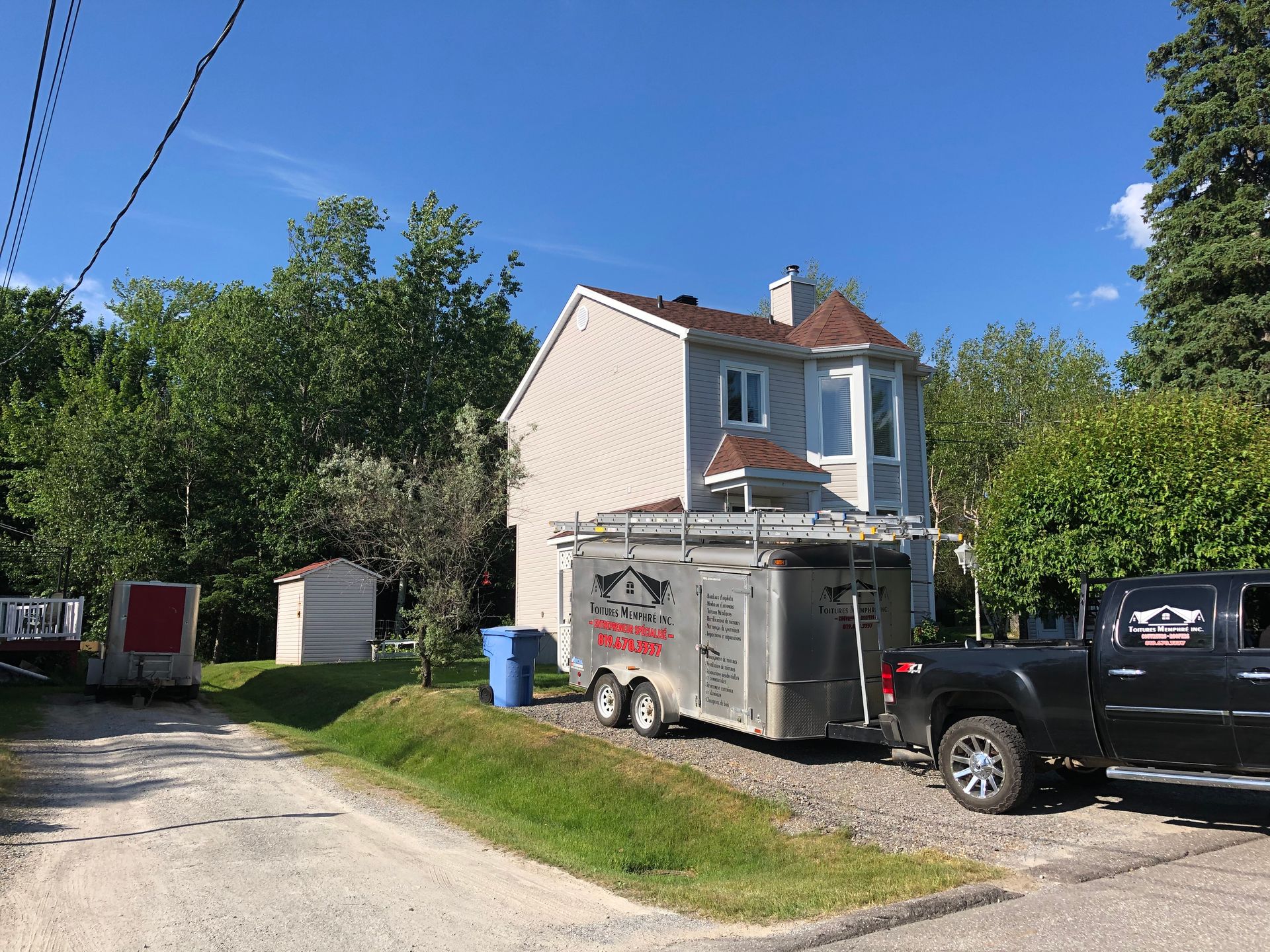 Un camion est garé devant une maison avec une remorque attachée.