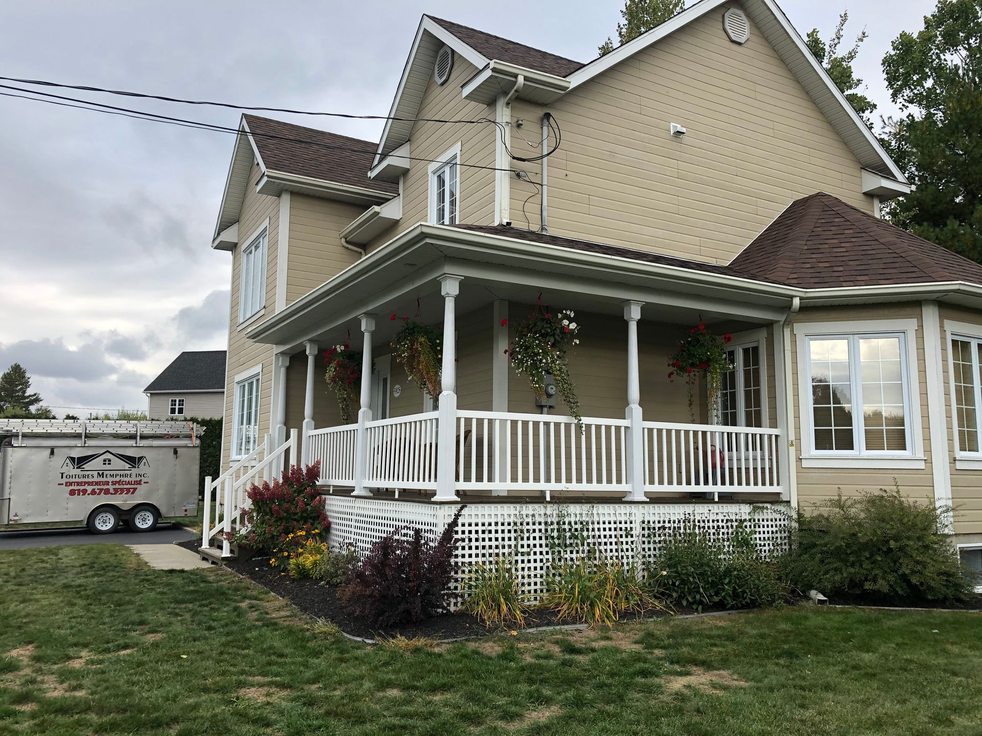 Une grande maison avec un grand porche et une caravane garée devant.