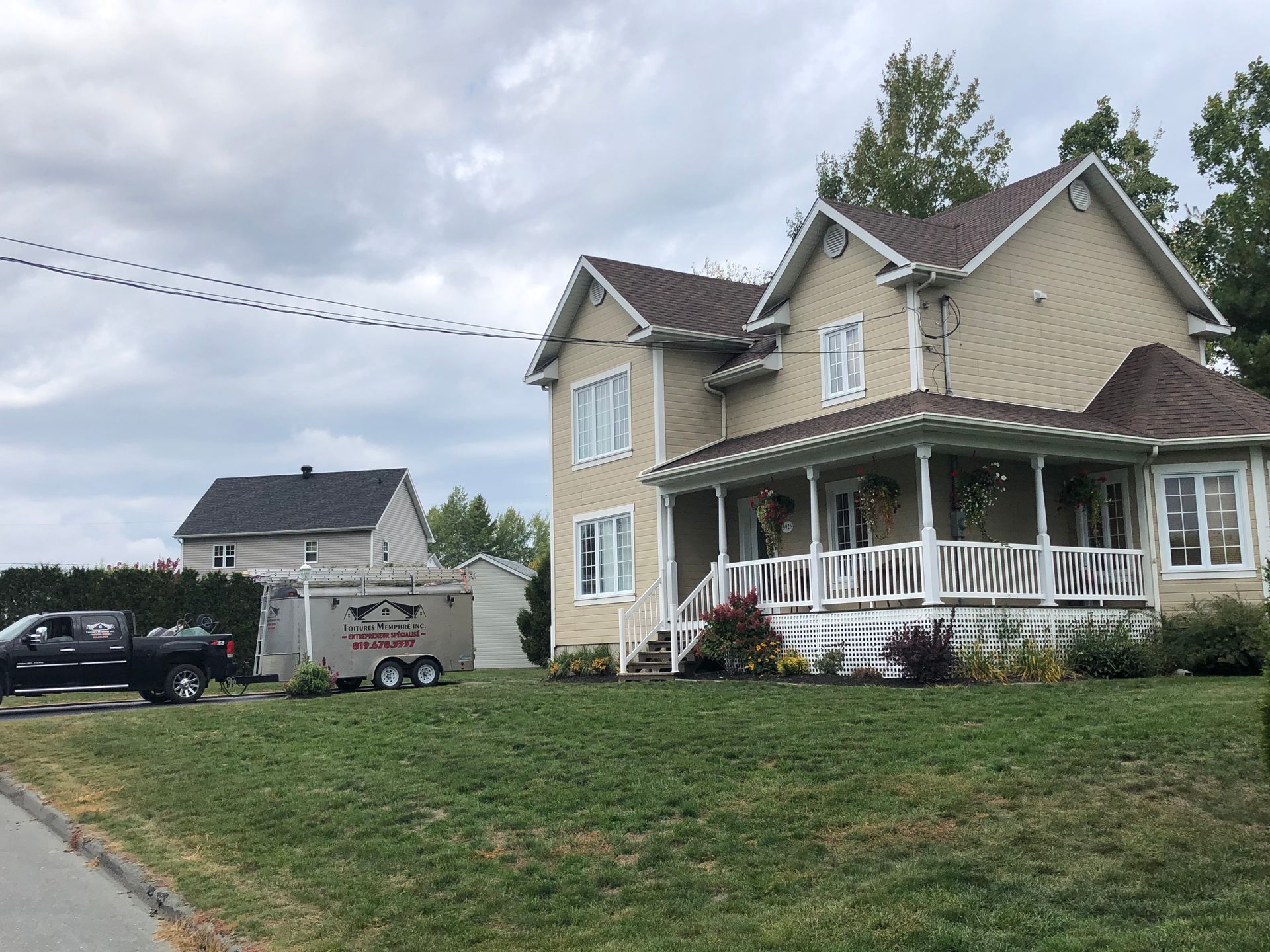 Une grande maison avec un grand porche et un camion garé devant.