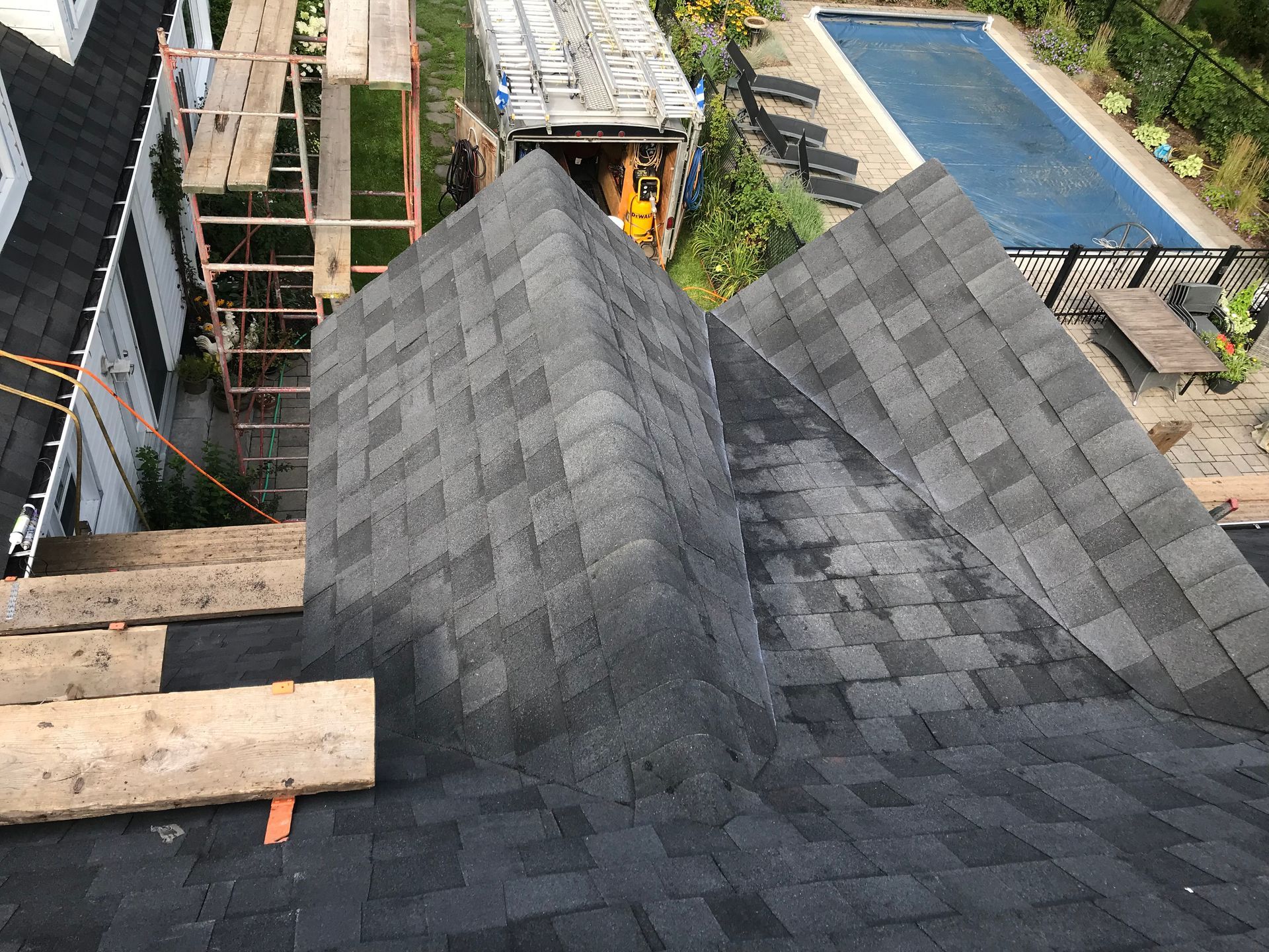 Un toit avec des bardeaux en cours d'installation et une piscine en arrière-plan